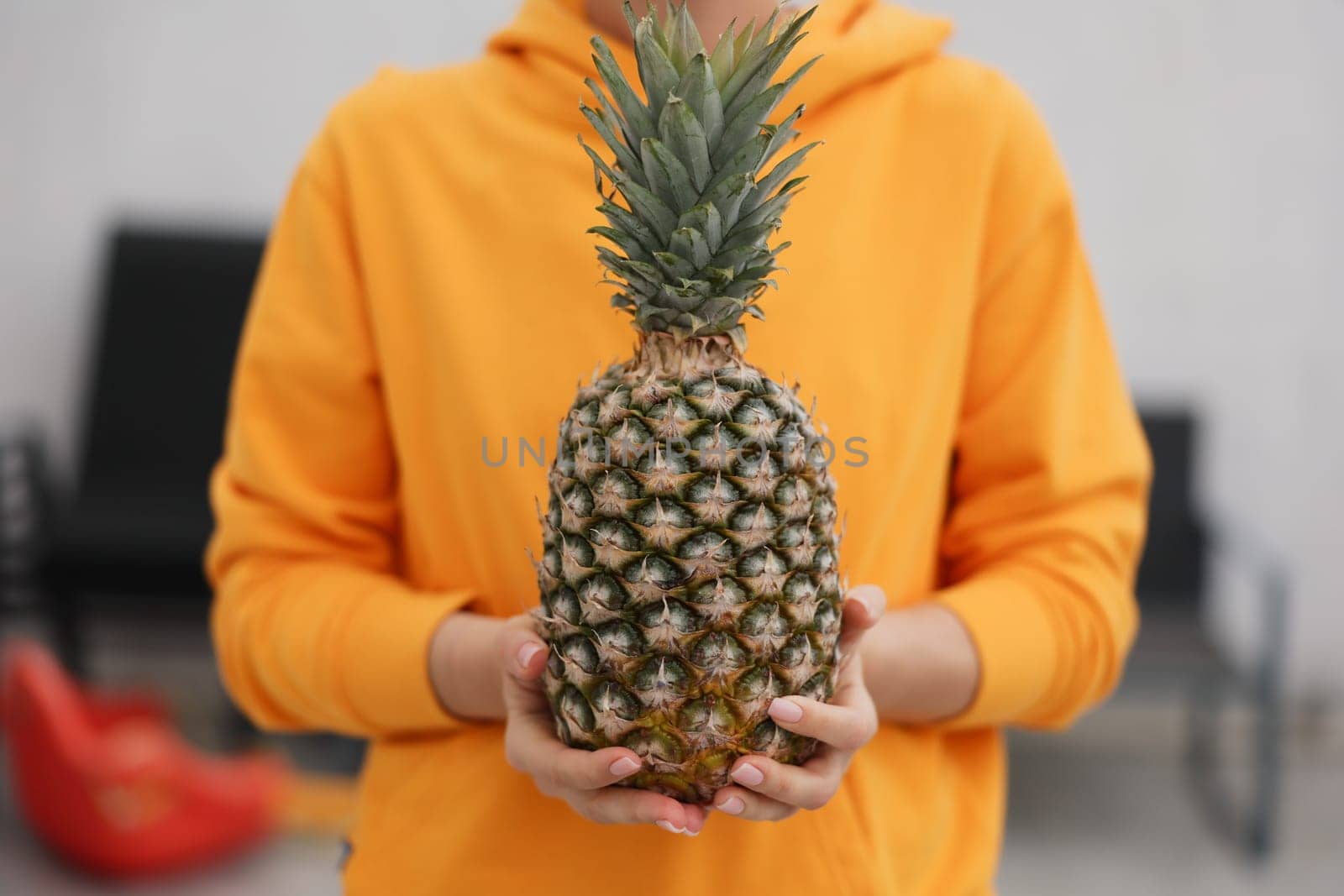 A vibrant and cheerful person holding a ripe pineapple, truly embodying freshness and a delightful tropical vibe