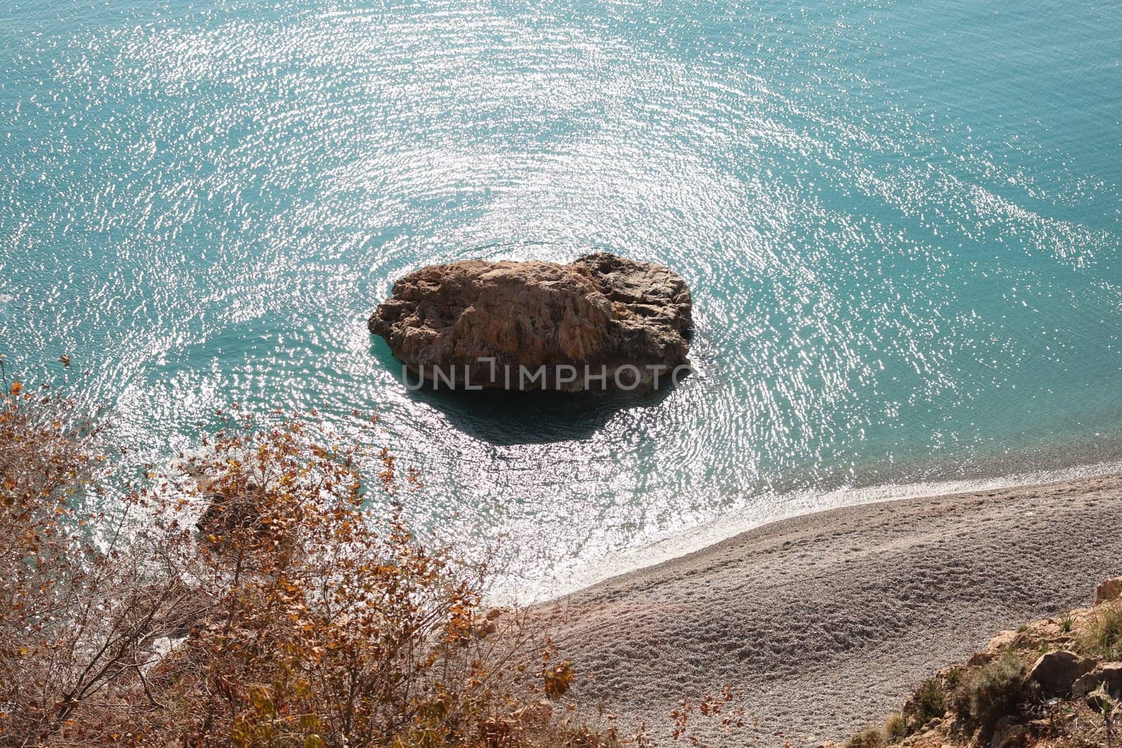 A tranquil view of a solitary rock in calm waters, showcasing the beauty of natures exquisite coastline