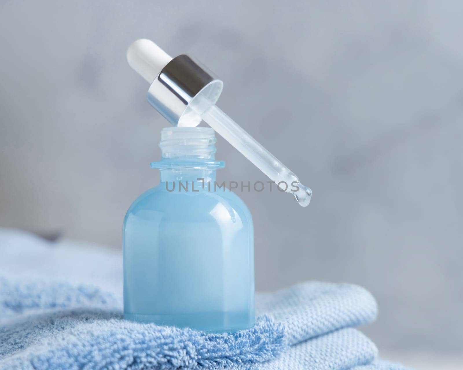 White cream squeeze tube on white marble table against green plant and cosmetic bottles in bathroom, close up, packaging mockup. Natural product for face care