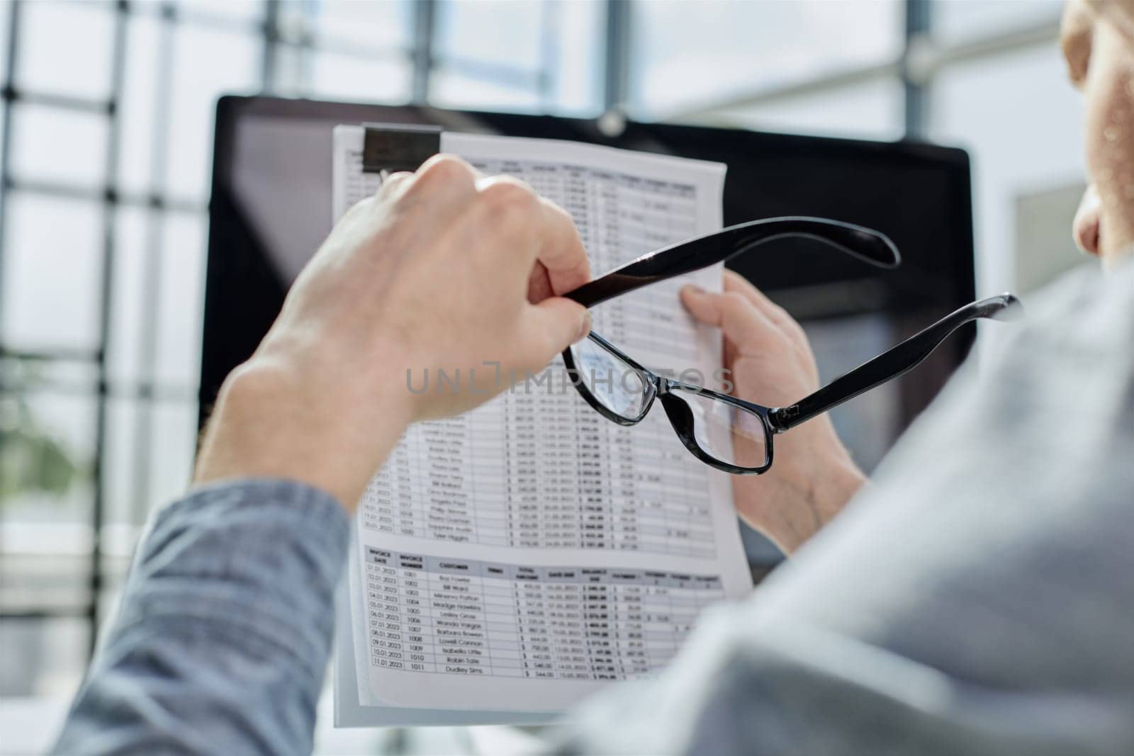Close-up of a financial businessman holding an information sheet in his hands, reading the company's financial statements for making a financial plan.