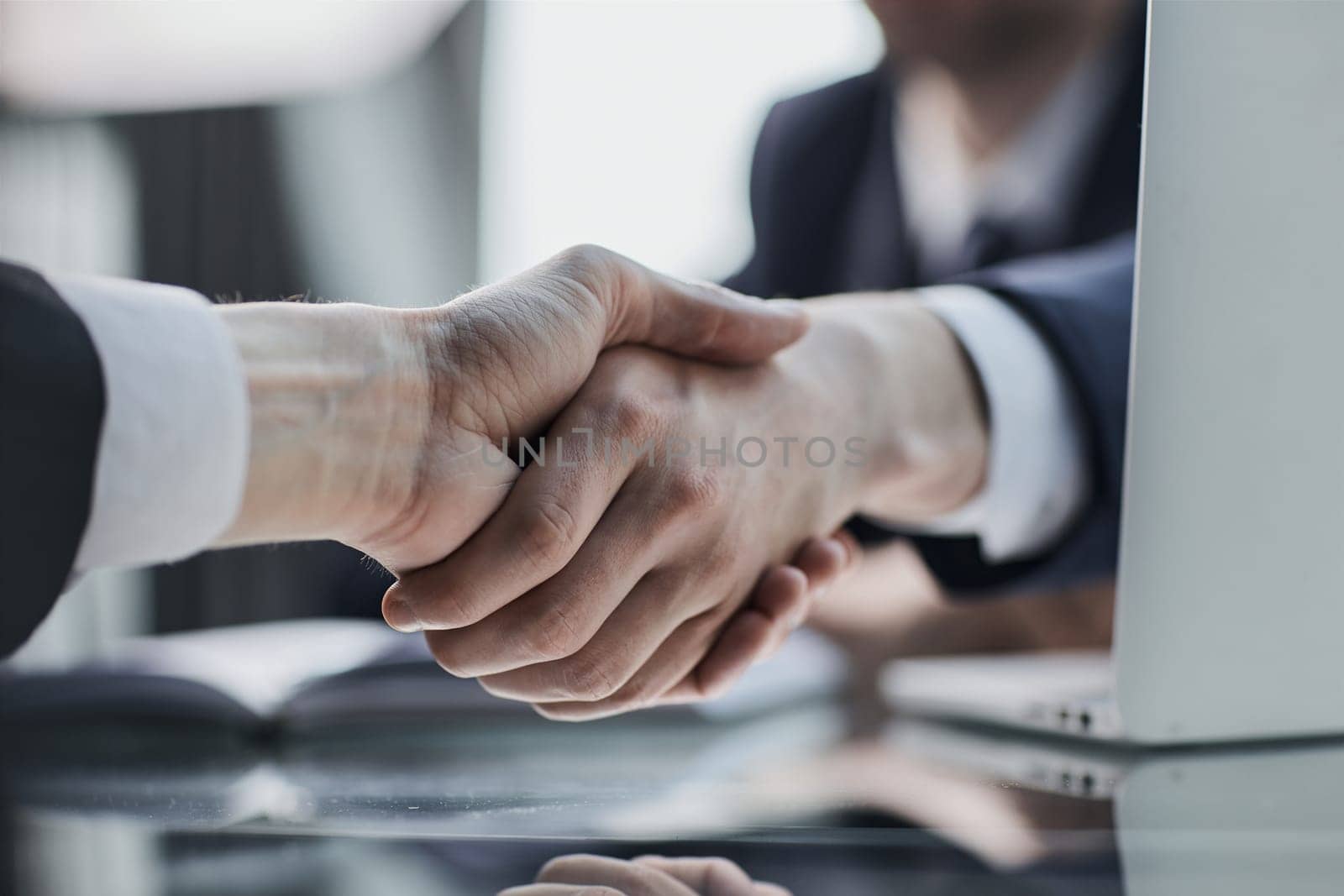 Close up of greeting handshake, young businessman hands shaking over conference table