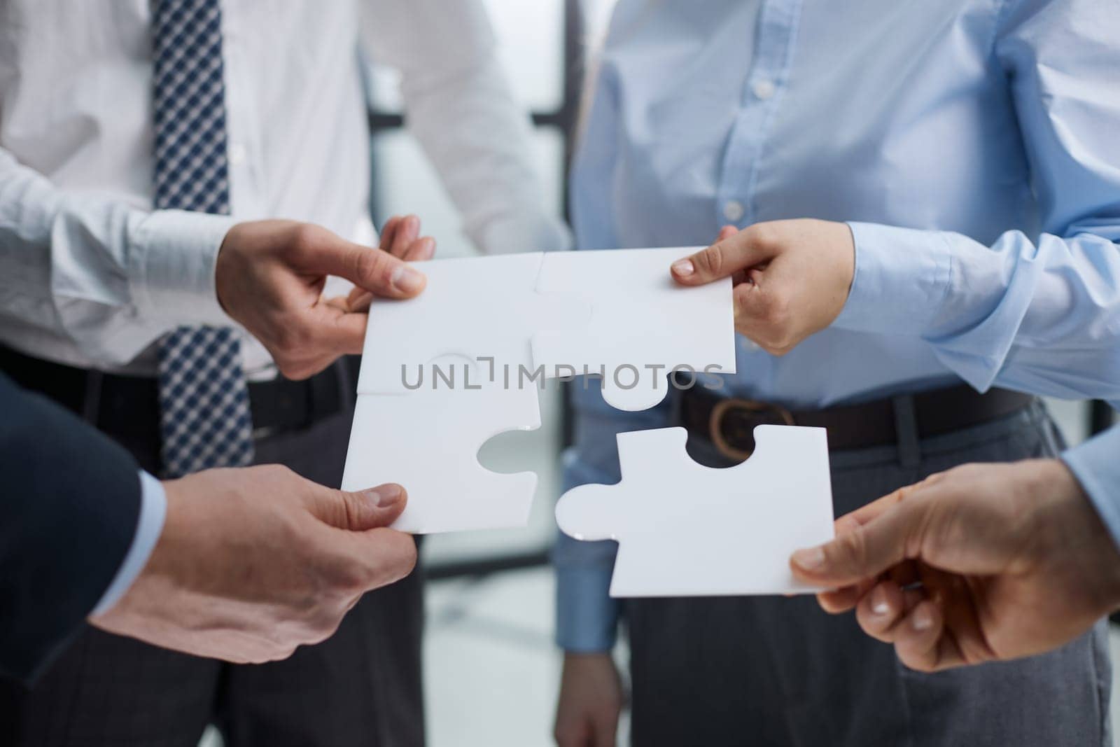 The team assembles the puzzle while standing in the office. joint solution concept