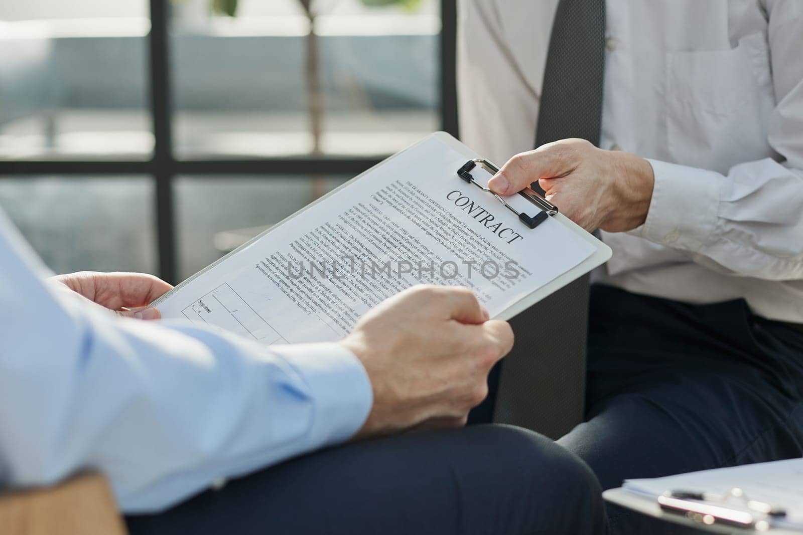 Close-up of businessmen looking at contract close-up while sitting in office