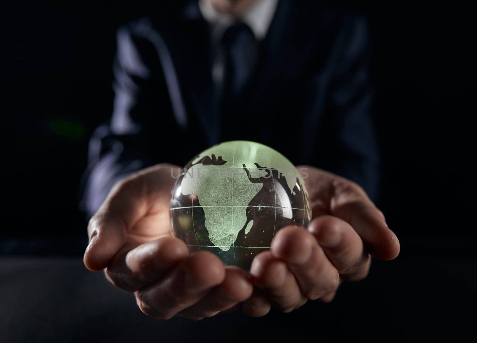 A man holds a glowing globe in his hands. close-up on a black background