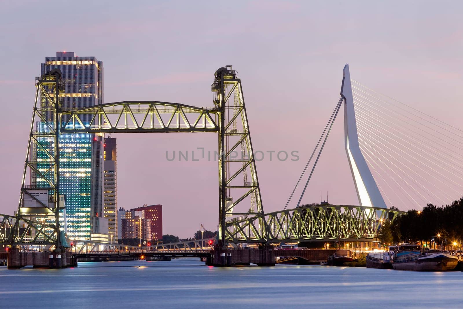 Twilight cityscape of Rotterdam with De Hef on the left and the Erasmus bridge on the right.