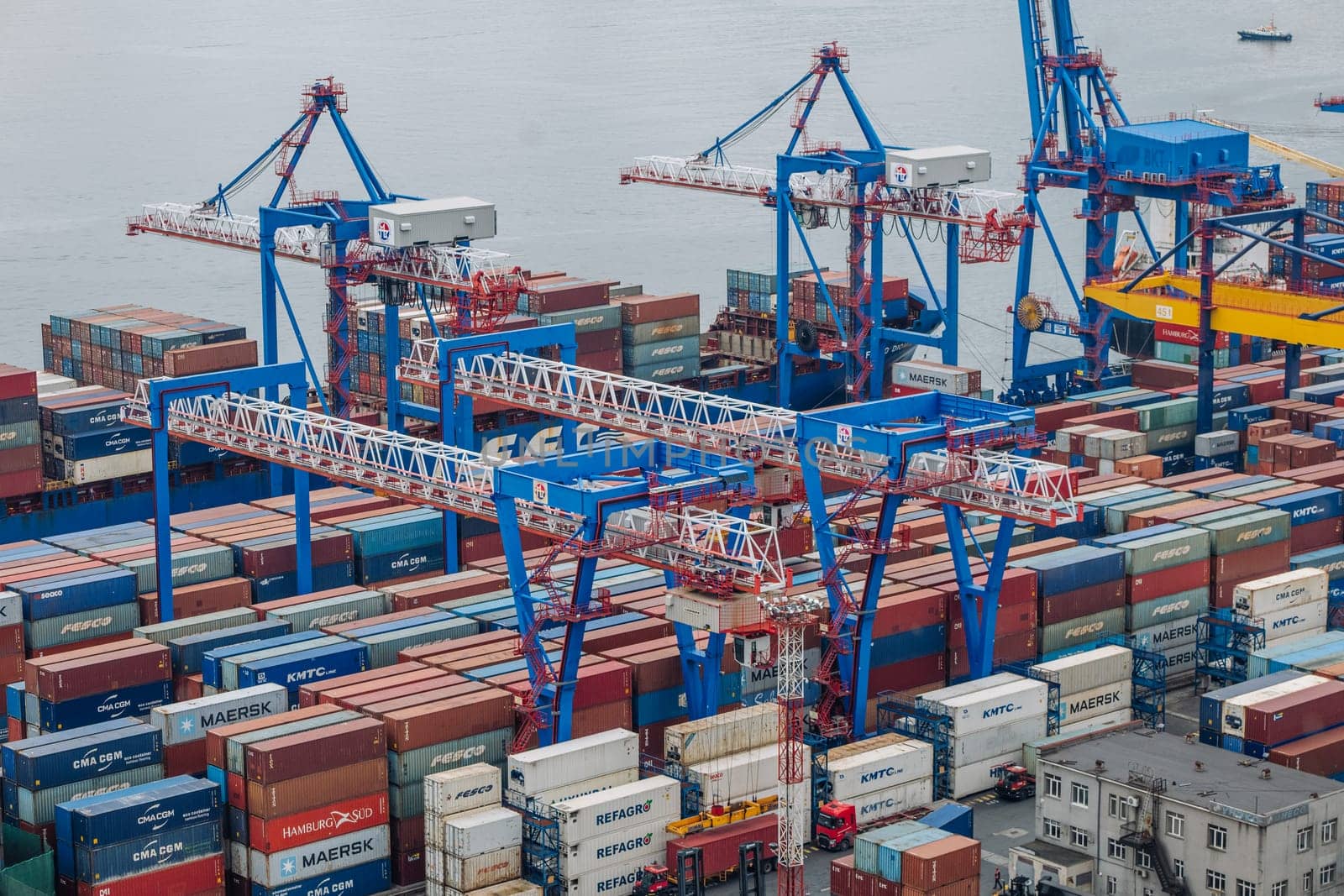 Industrial cargo cranes lifting multicolored shipping containers at busy russian maritime terminal, highlighting international commerce