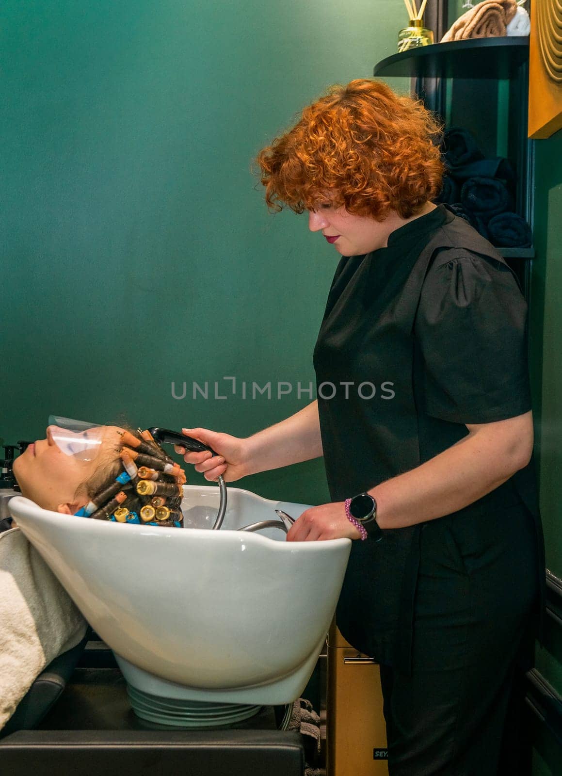 The client's hair is washed in a beauty salon. The client has curlers on his head. The hair is curled so that the hair is curly and wavy.