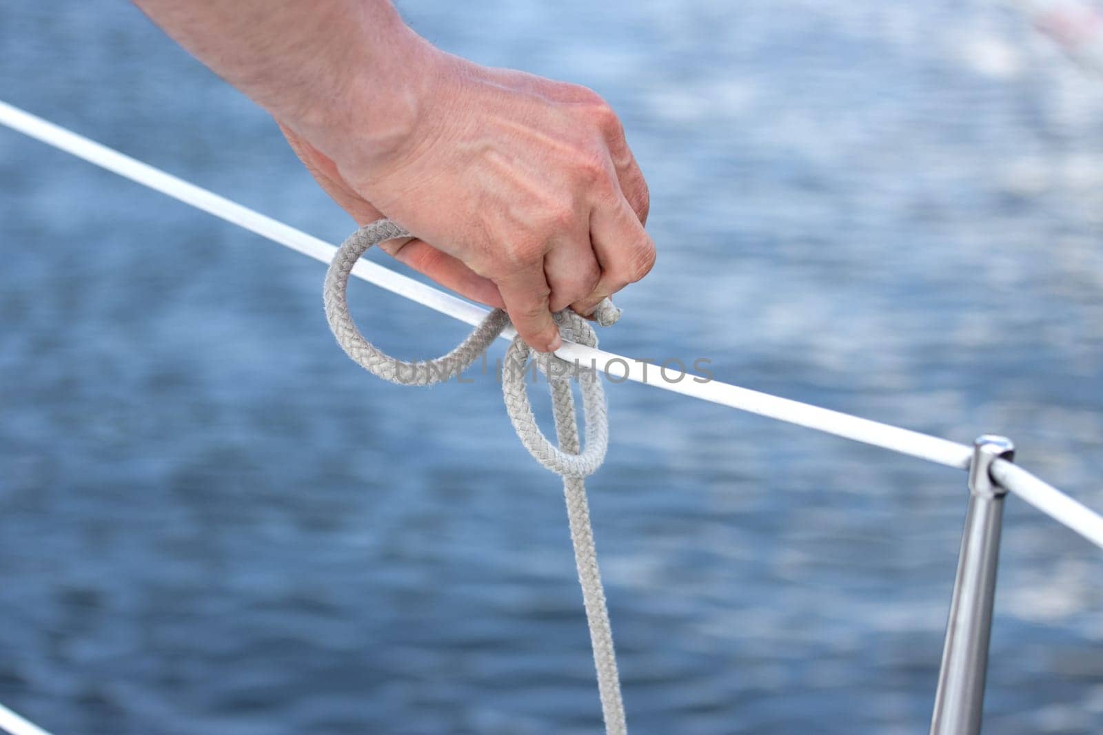 A detailed closeup shot of a hand expertly tying a knot on a boat, showcasing essential sailing techniques