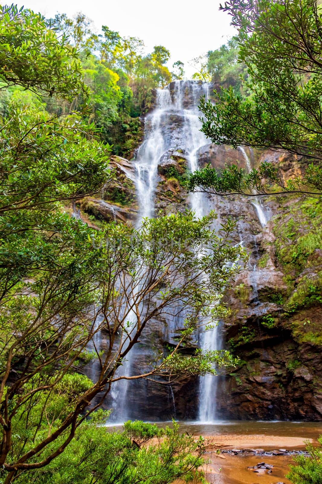 Waterfall seen through the vegetation of the dense tropical forest in Minas Gerais, Brazil