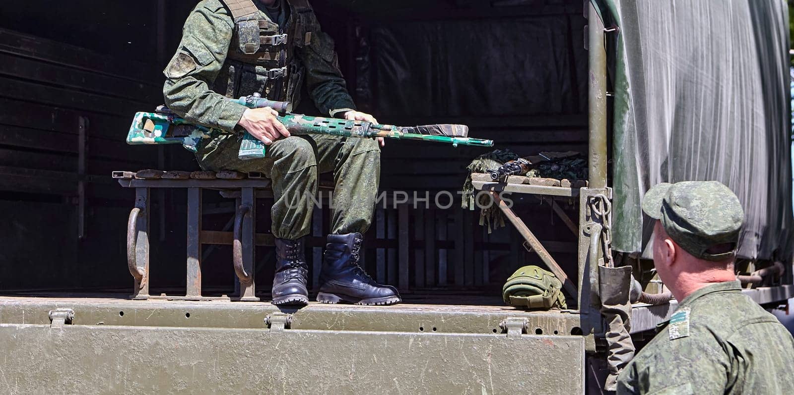 Soldiers unload firearms from a military truck. A soldier in the back of a truck.