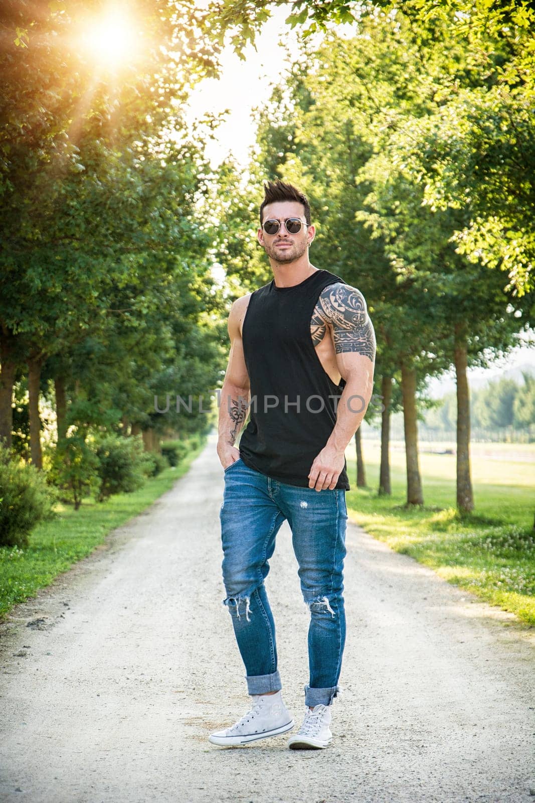 Photo of a man standing on a dirt road surrounded by trees by artofphoto