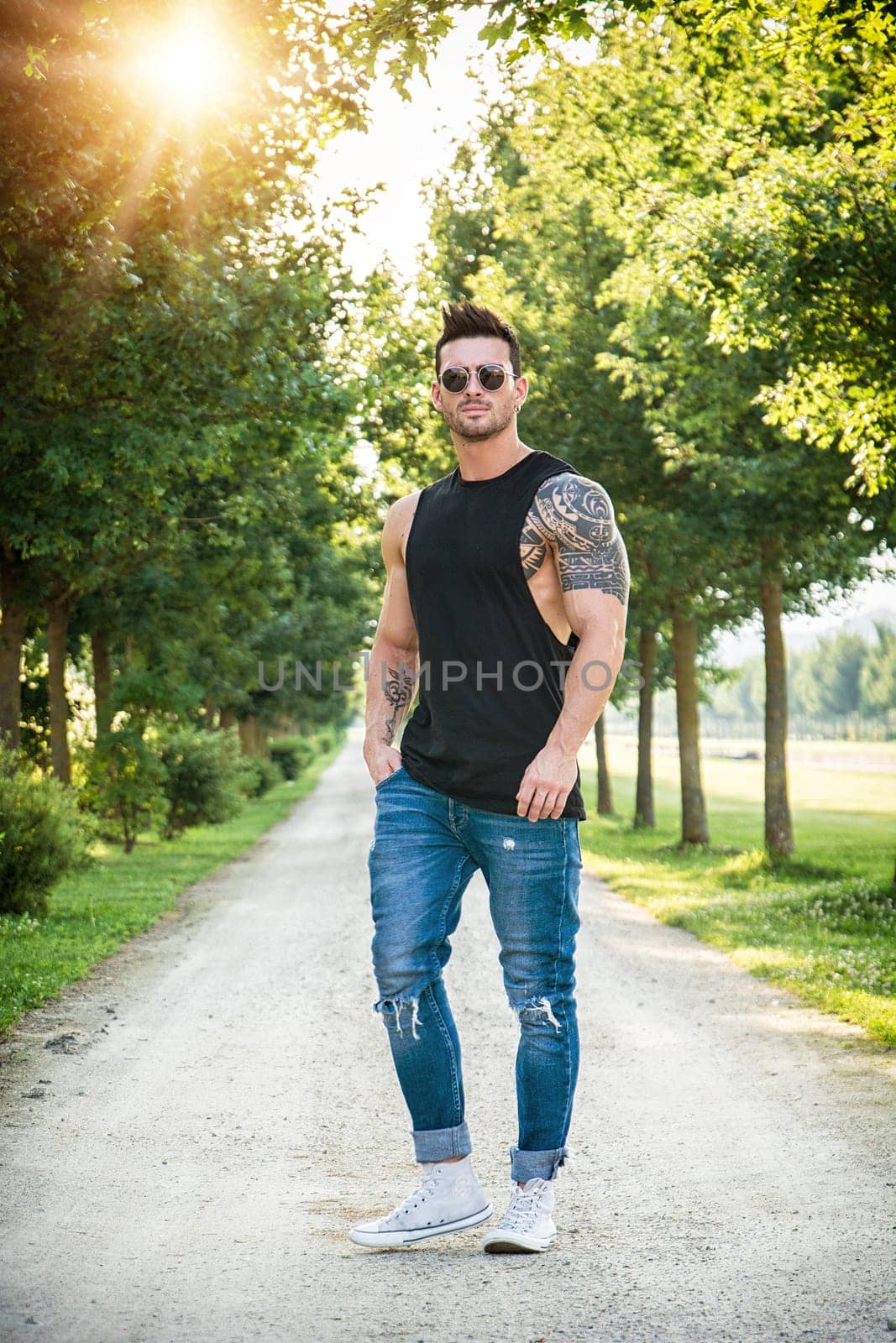 A man standing on a dirt road with trees in the background. Photo of a man standing on a dirt road surrounded by trees