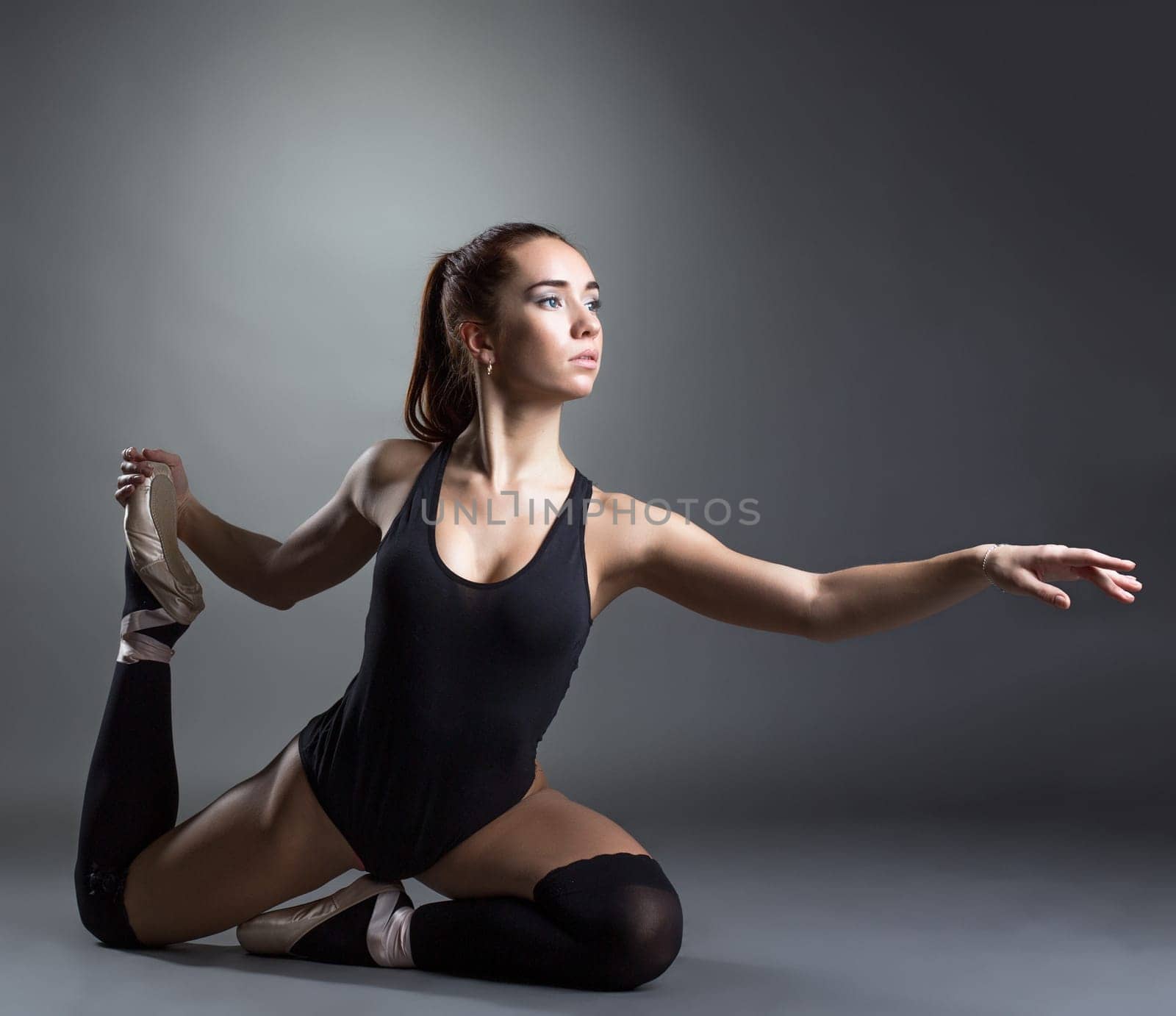 Image of inspired ballerina posing in studio, on gray background