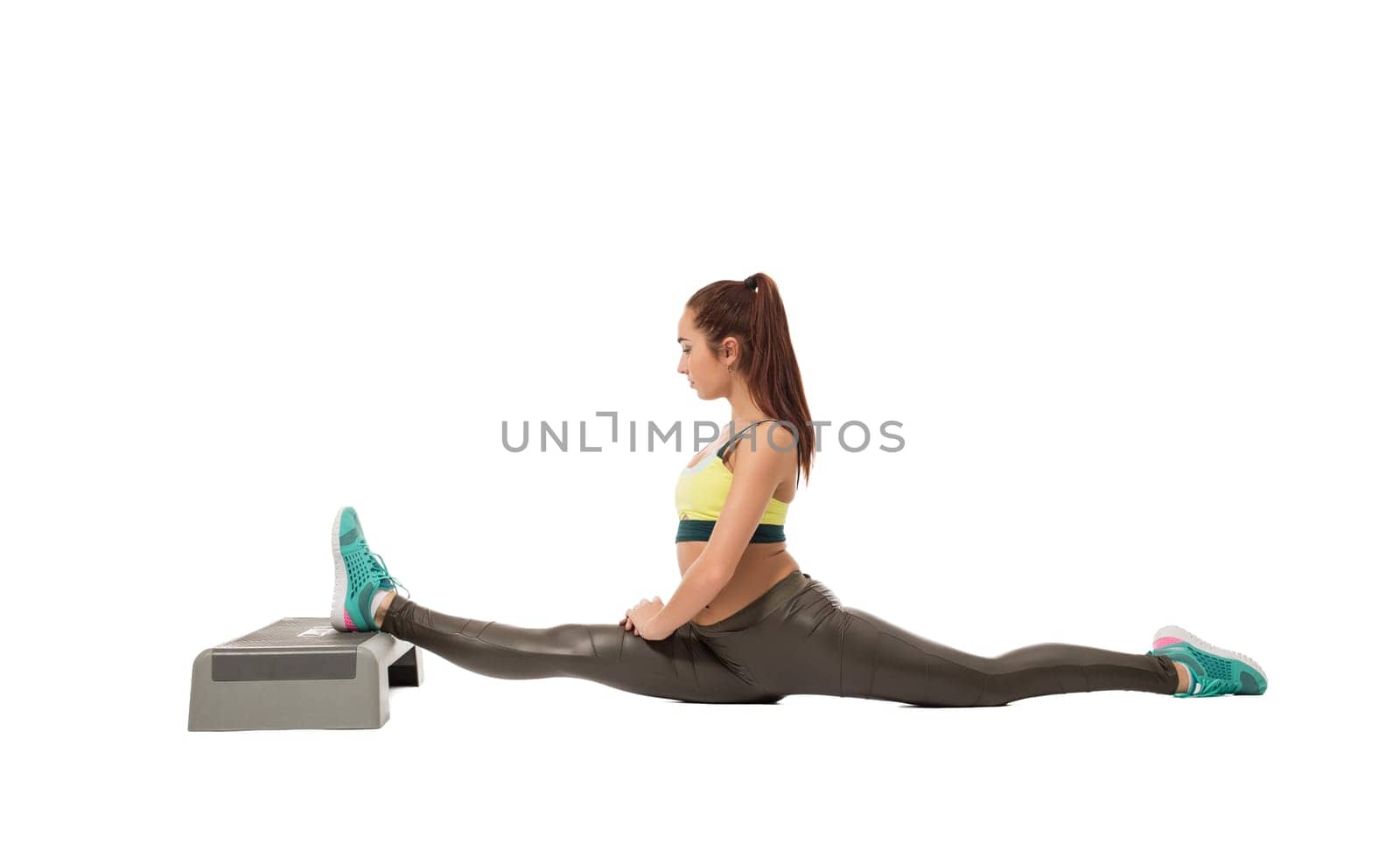 Sporty girl doing difficult stretching exercise, isolated on white