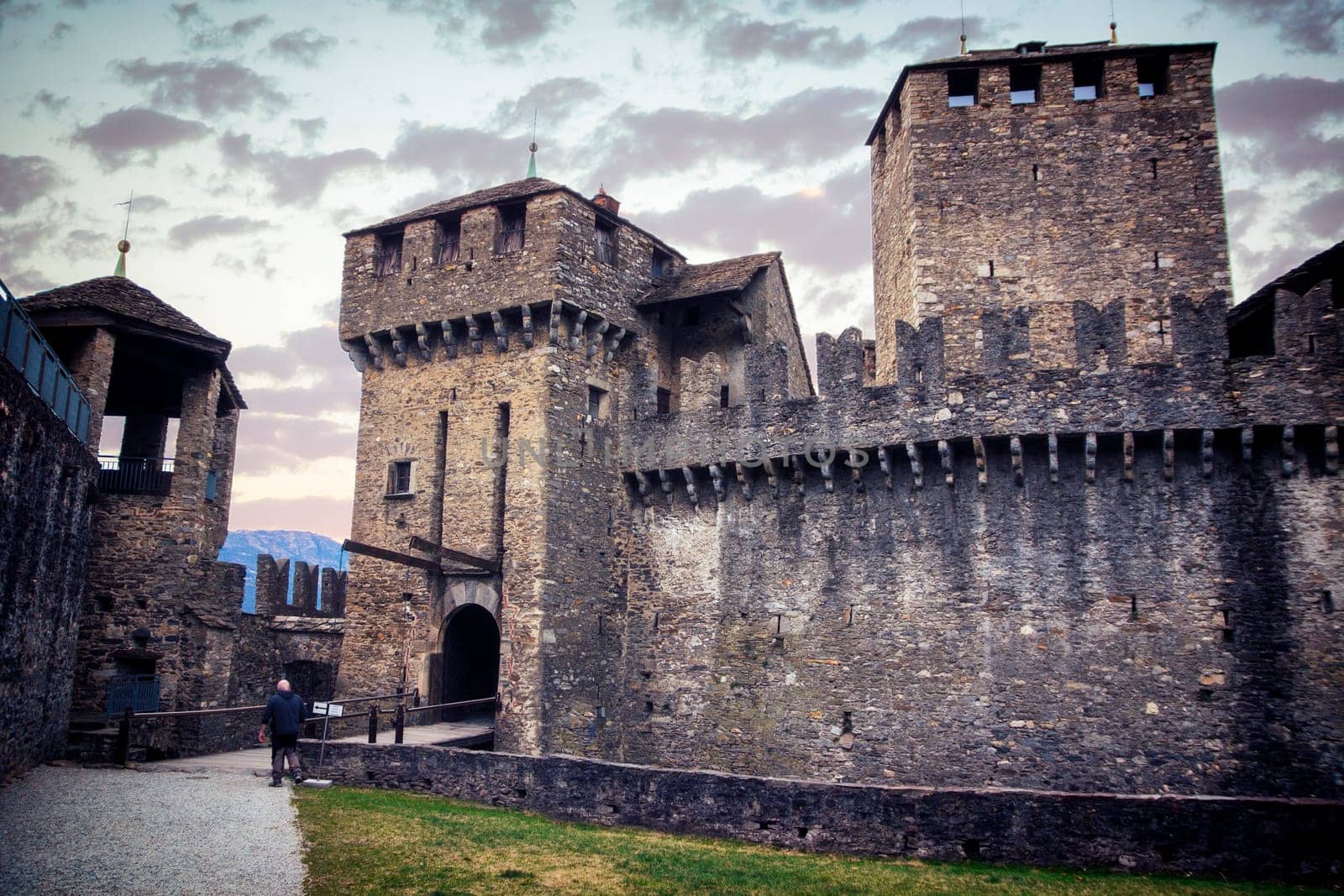 A stone castle with a bridge going through it. Photo of a medieval stone castle with a bridge crossing through it in Bellinzona, Switzerland