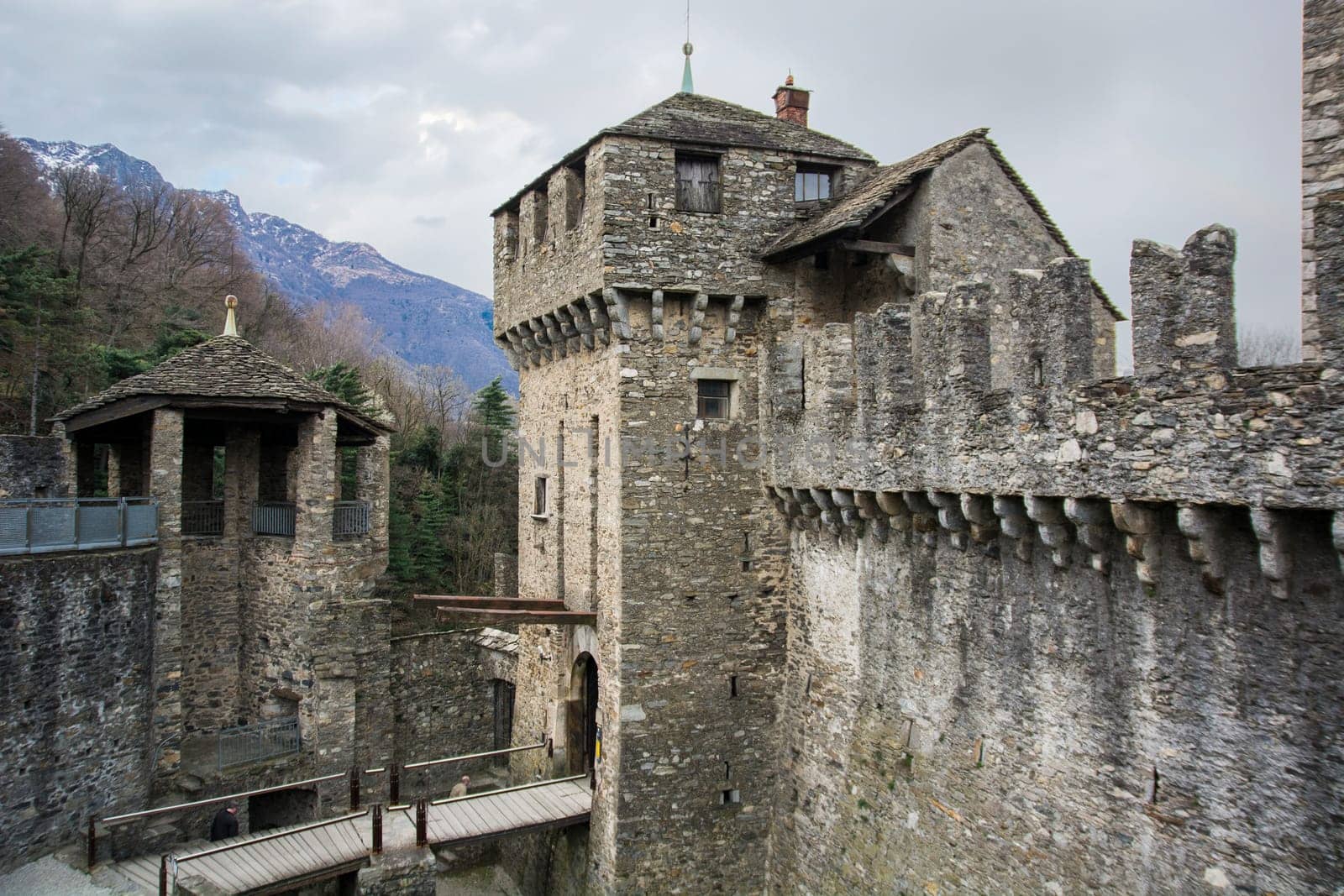A stone castle with a bridge going through it. Photo of a medieval stone castle with a bridge crossing through it in Bellinzona, Switzerland
