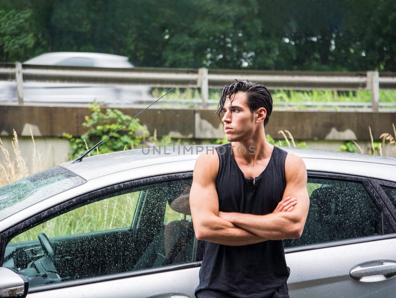 A man standing in front of a car with his arms crossed