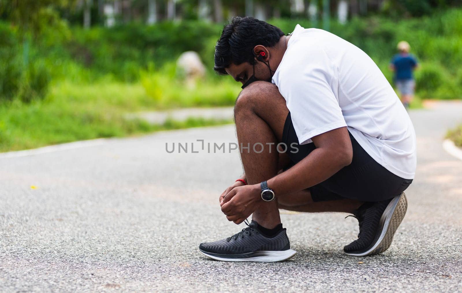 Close up Asian sport runner black man wear watch sitting he trying shoelace running shoes getting ready for jogging and run at the outdoor street health park, healthy exercise workout concept