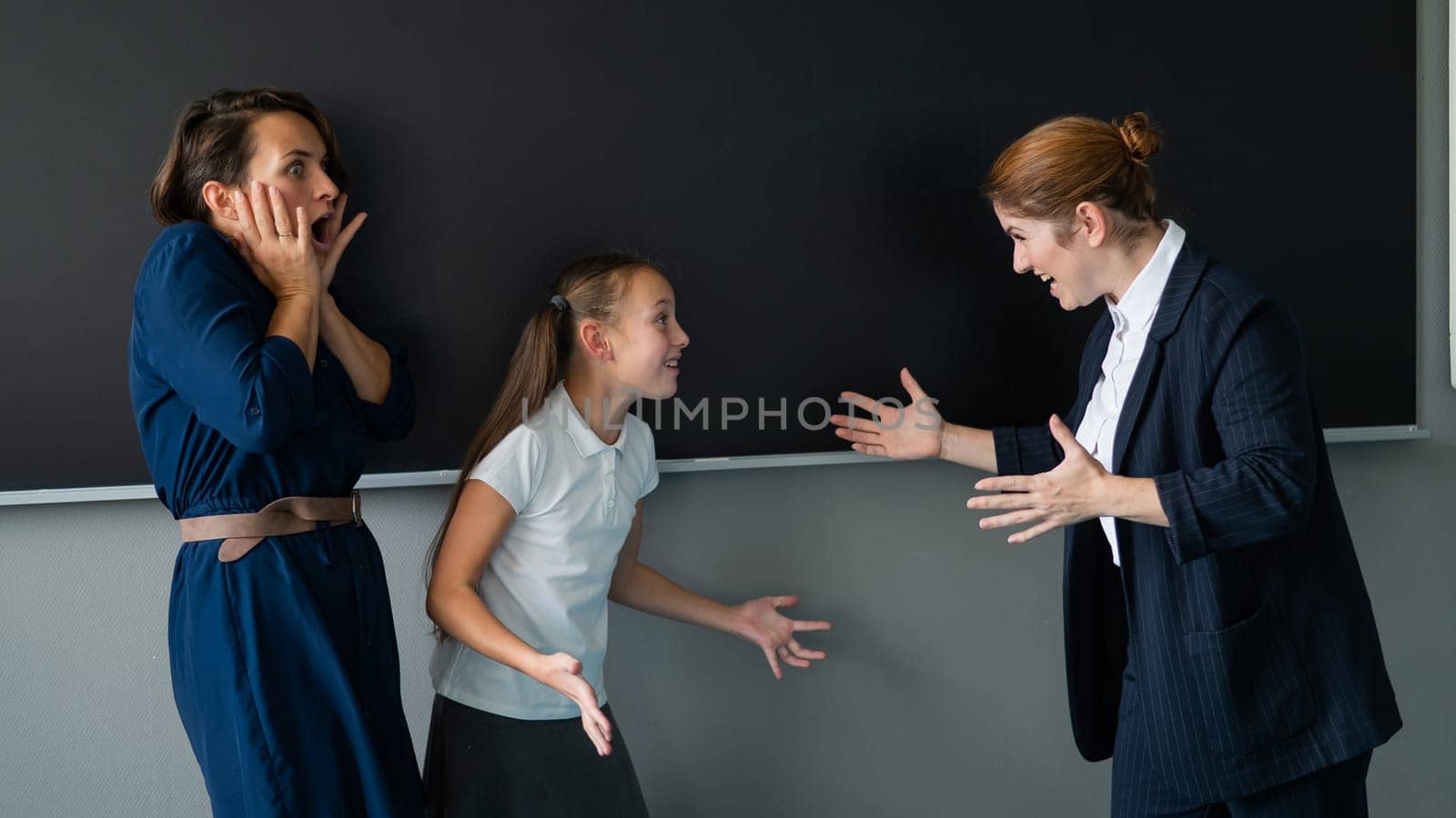 The teacher screams at the schoolgirl and her mother standing at the blackboard. by mrwed54