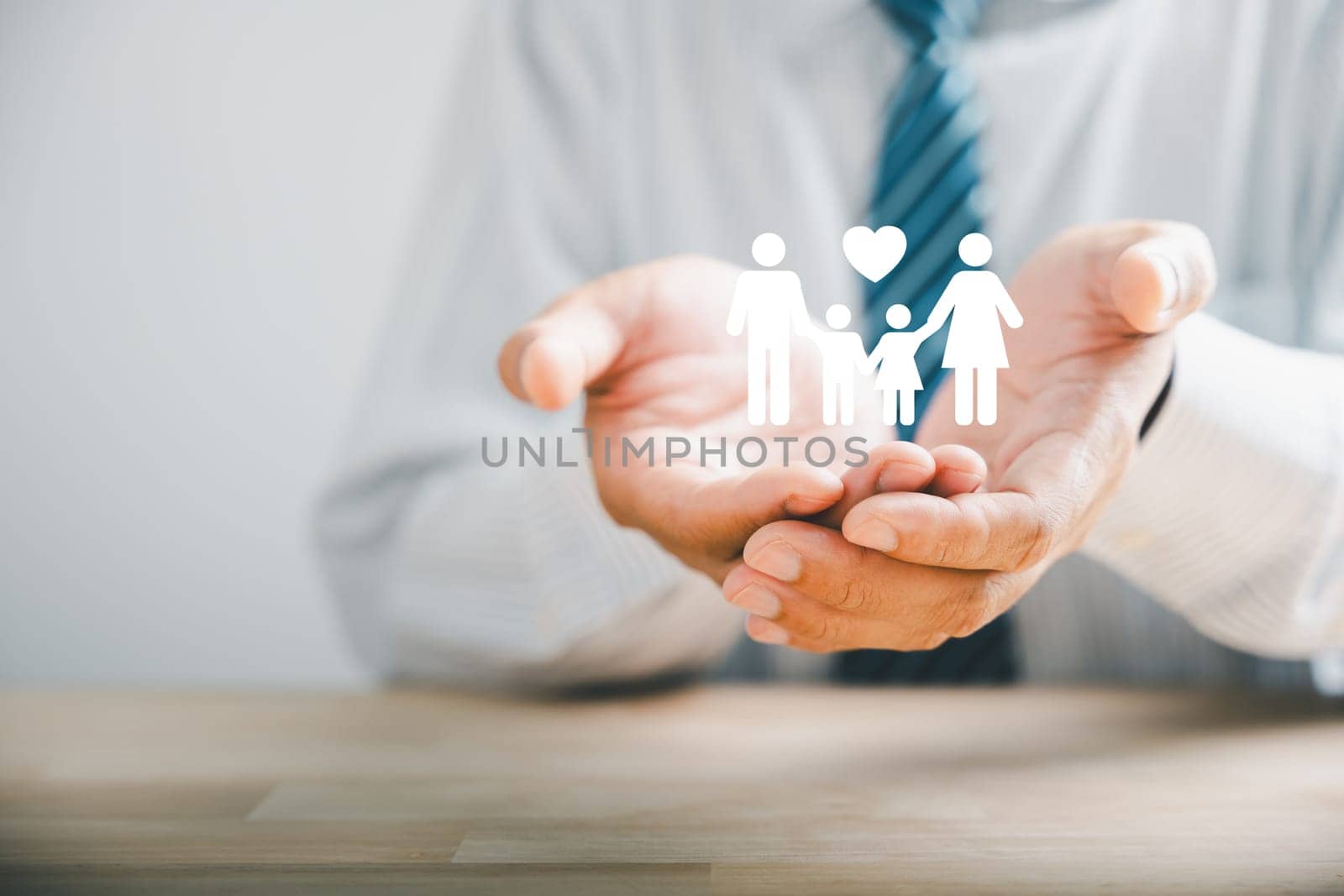 Safety for families, Businessman protective gesture complements young family silhouette. Health and house insurance icons symbolize protection, supporting the concept of family life insurance.