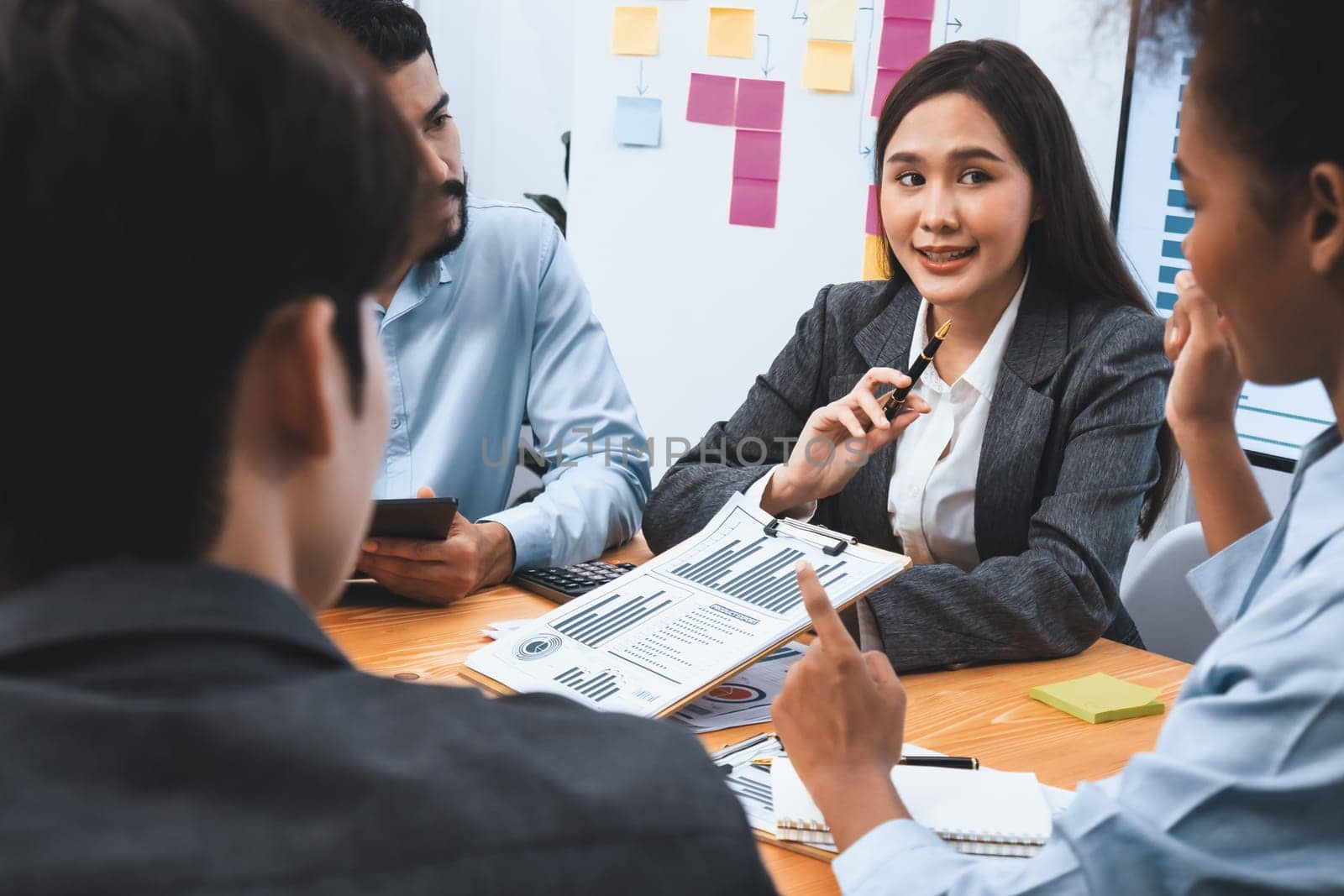 Multiracial analyst team use BI dashboard data to analyze financial report on meeting table. Group of diverse business people utilize data analysis by FIntech for business marketing decision. Concord