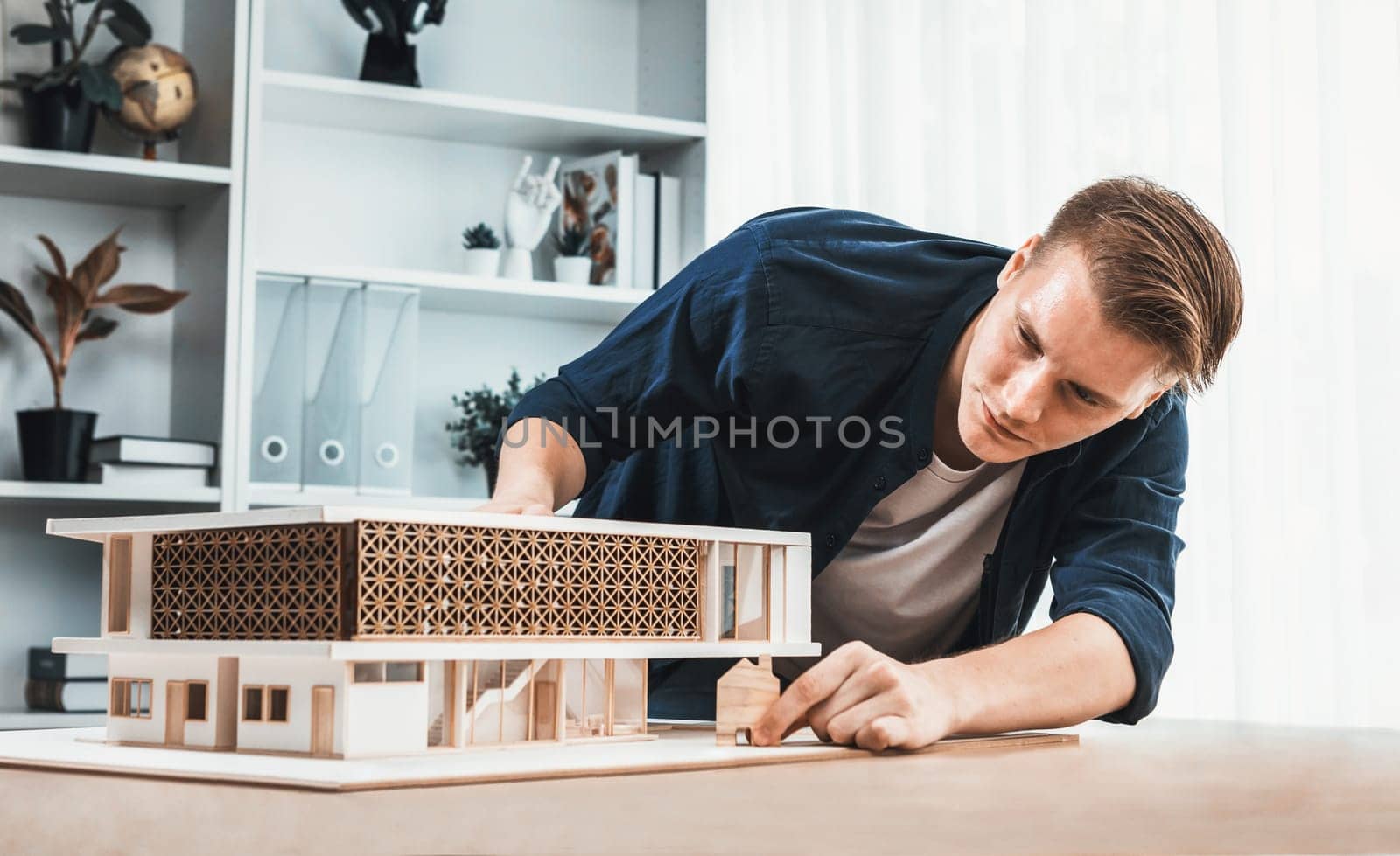 Architect designer studies elegant house model, reviewing structure design for improvement with construction plan on table. Creativity and innovation in architectural design. Iteration