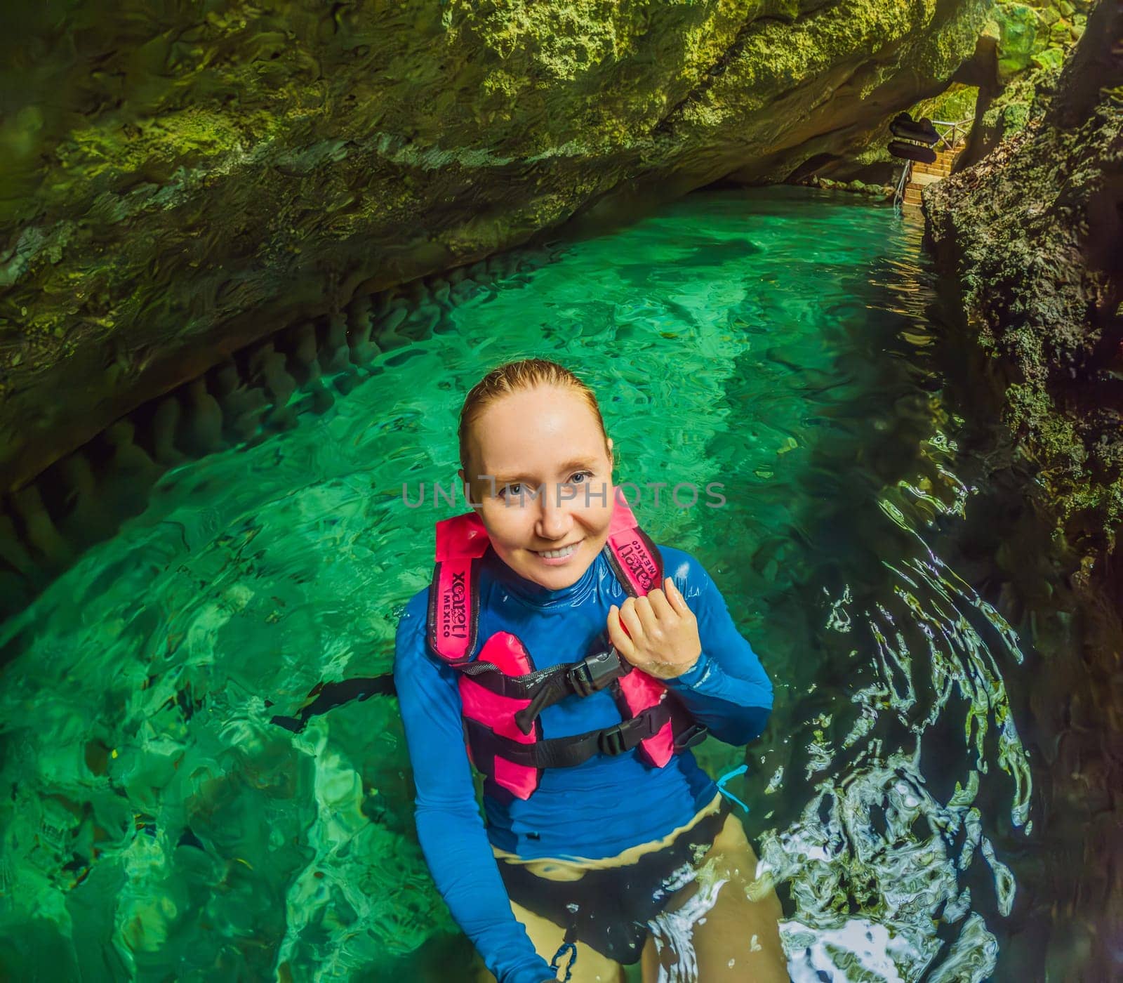 09.12.24, Playa Del Carmen, Mexico: Woman tourist in the water of a cenote at Xcaret park wearing a marked life jacket. Mexican tourism in natural parks. Adventure, relaxation, and eco-tourism concept in Quintana Roo.