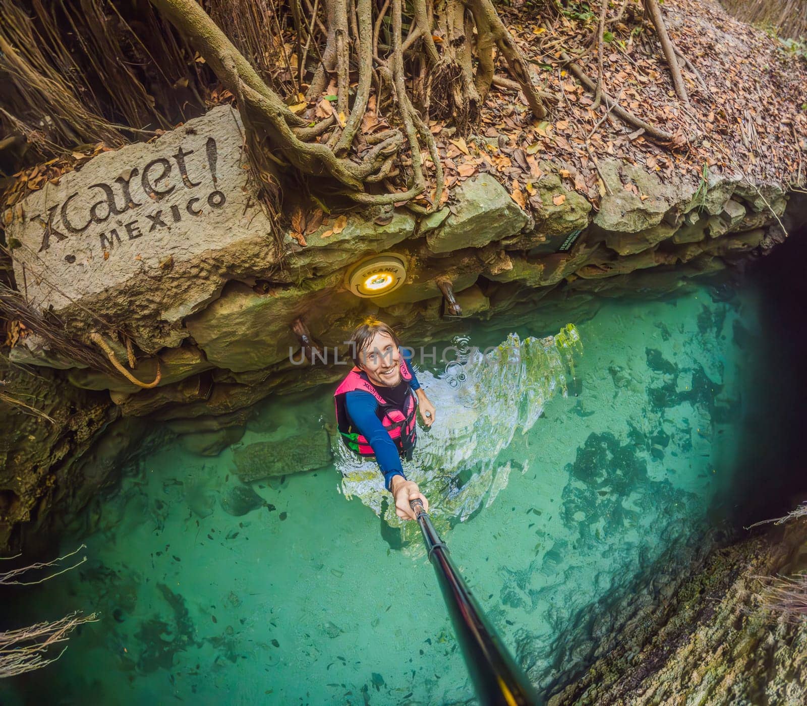 09.12.24, Playa Del Carmen, Mexico: Man tourist standing in the water of a cenote at Xcaret park wearing a marked life jacket. Mexican tourism in natural parks. Adventure, relaxation, and eco-tourism concept in Quintana Roo.