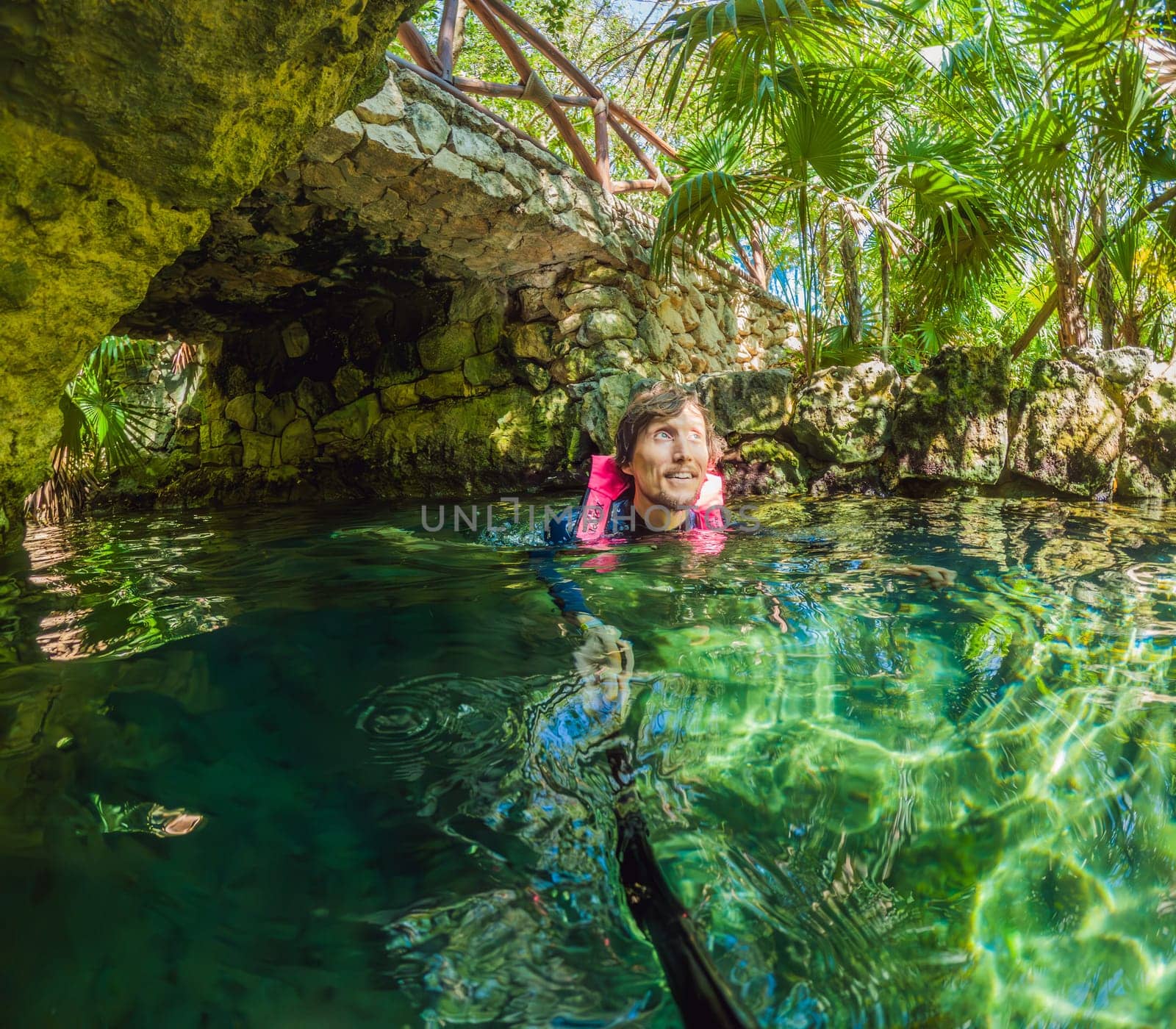 09.12.24, Playa Del Carmen, Mexico: Man tourist standing in the water of a cenote at Xcaret park wearing a marked life jacket. Mexican tourism in natural parks. Adventure, relaxation, and eco-tourism concept in Quintana Roo.