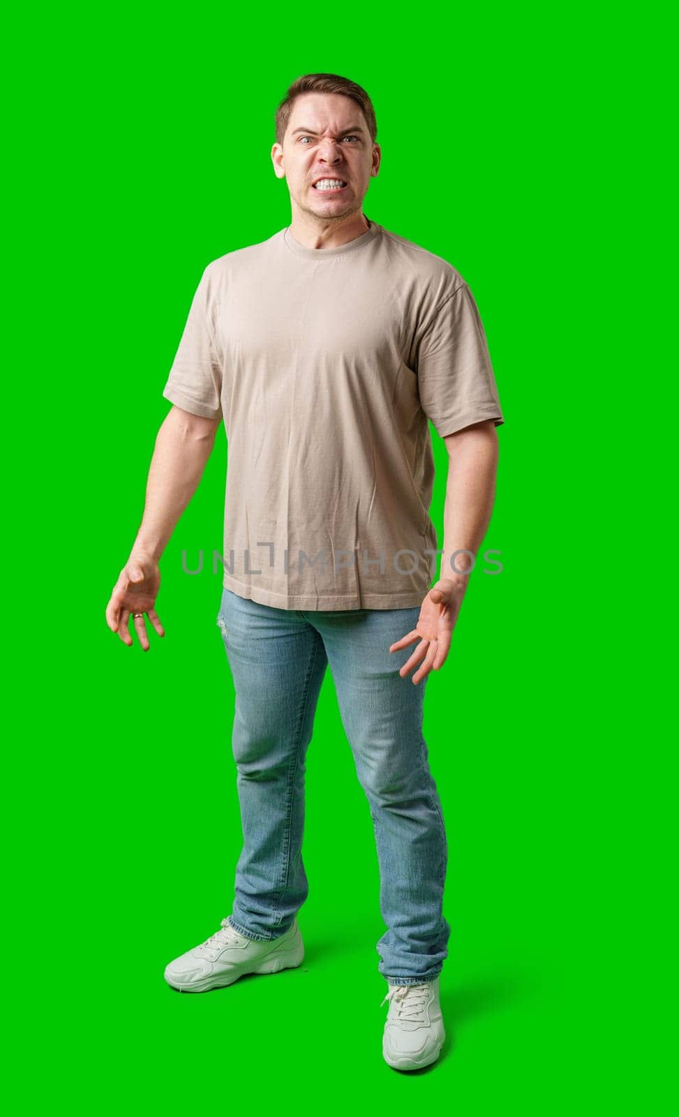 Man expressing intense frustration while standing against a bright green background in studio