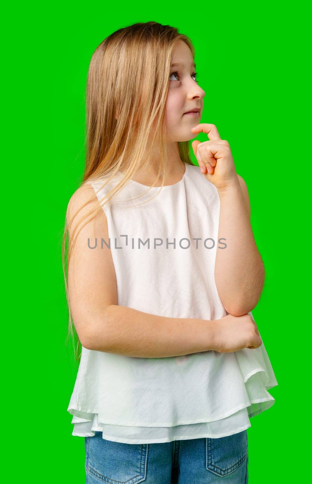 Young girl with long hair pointing upwards, showcasing her idea against a bright green background in studio