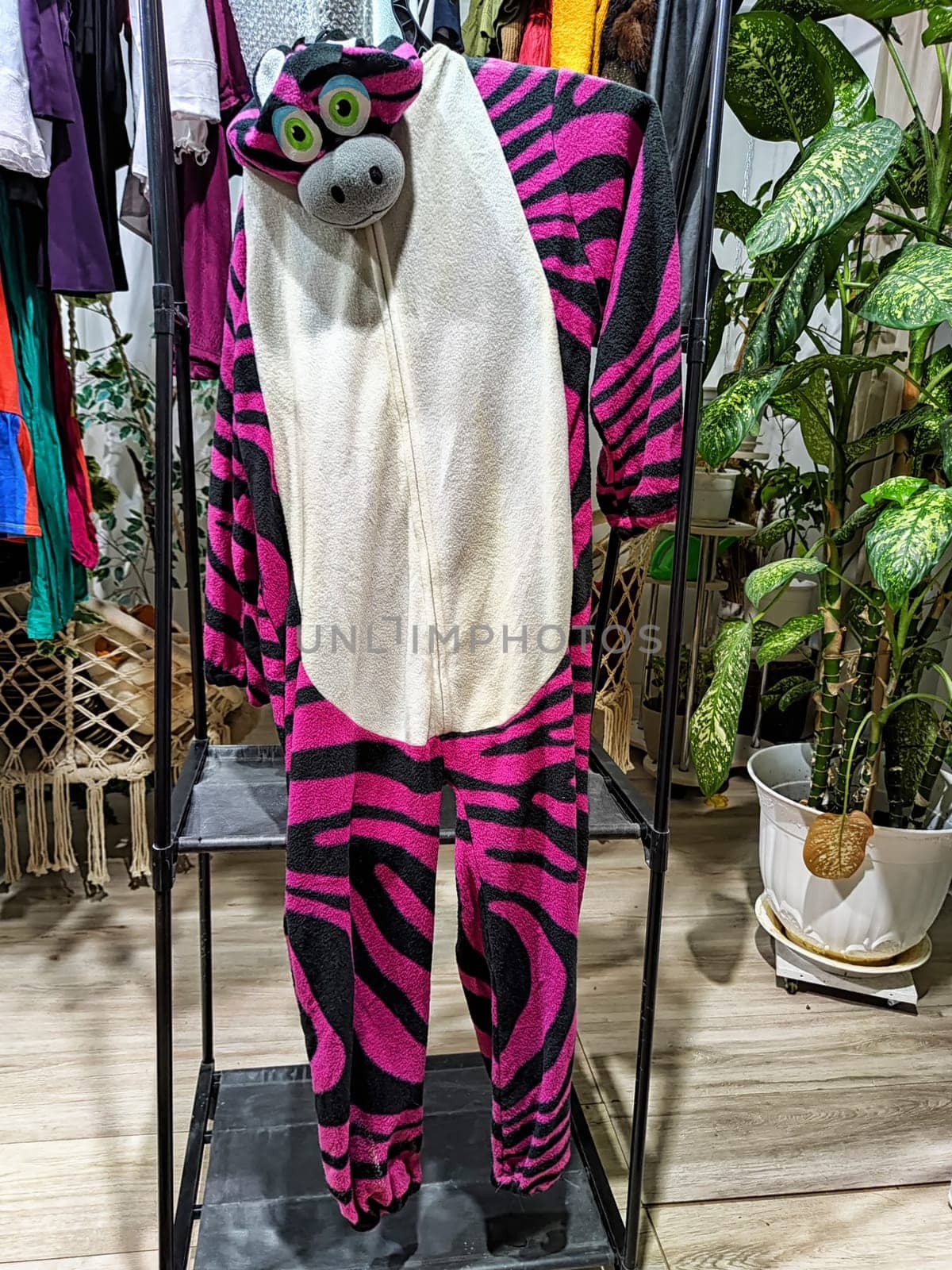 Discover a vibrant zebra onesie among a variety of second-hand clothing at a garage sale promoting eco-friendly choices.