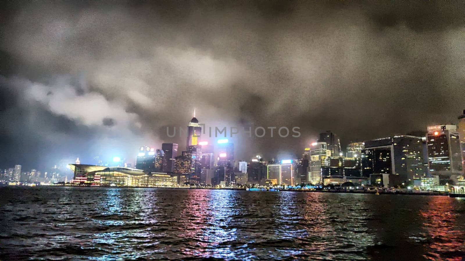 Hong Kong, China - April 06, 2024 - Victoria Bay showcases Hong Kong's iconic skyline at night, with skyscrapers illuminated against the dramatic clouds.