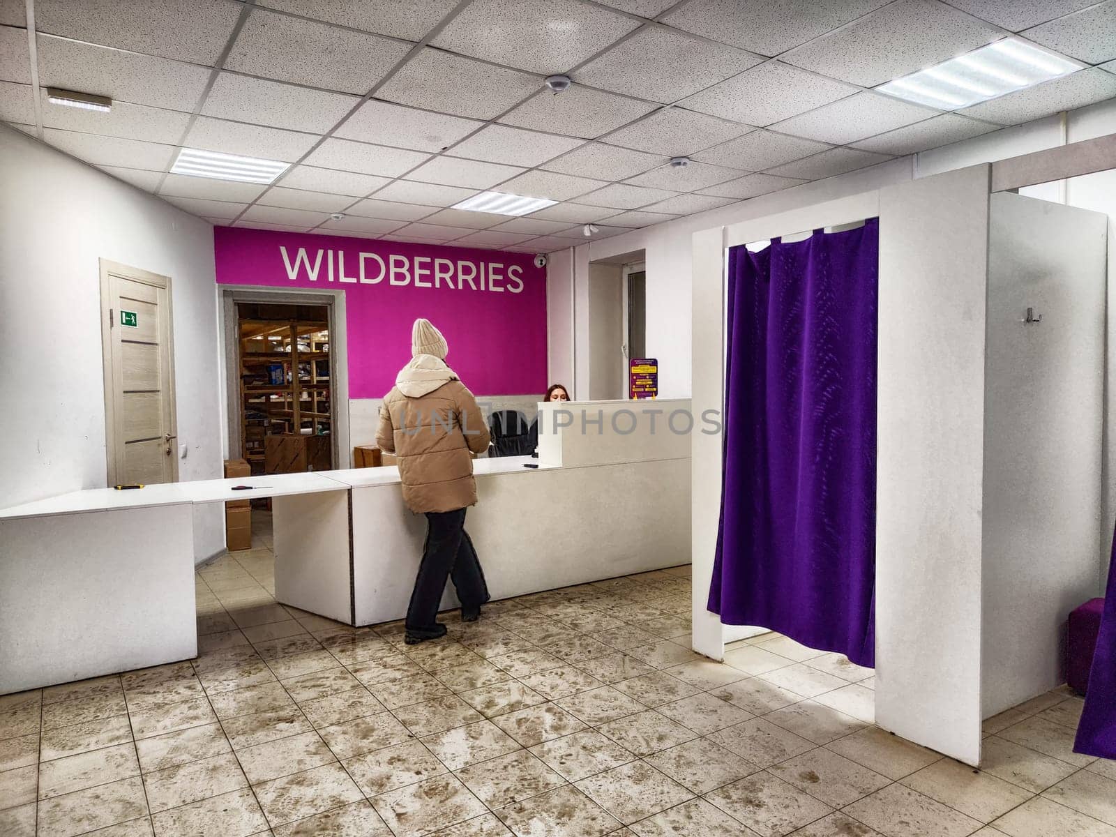 Kirov, Russia - December 09, 2024: Customer approaches the service desk in a modern retail space with purple walls and a welcoming atmosphere.