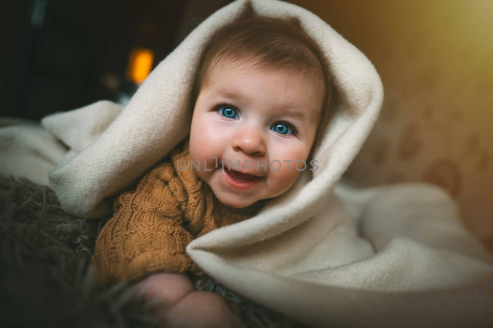 Smiling baby girl crawling on bed under the blanket. Adorable kid portrait. 5 month old child. Childhood concept. High quality photo