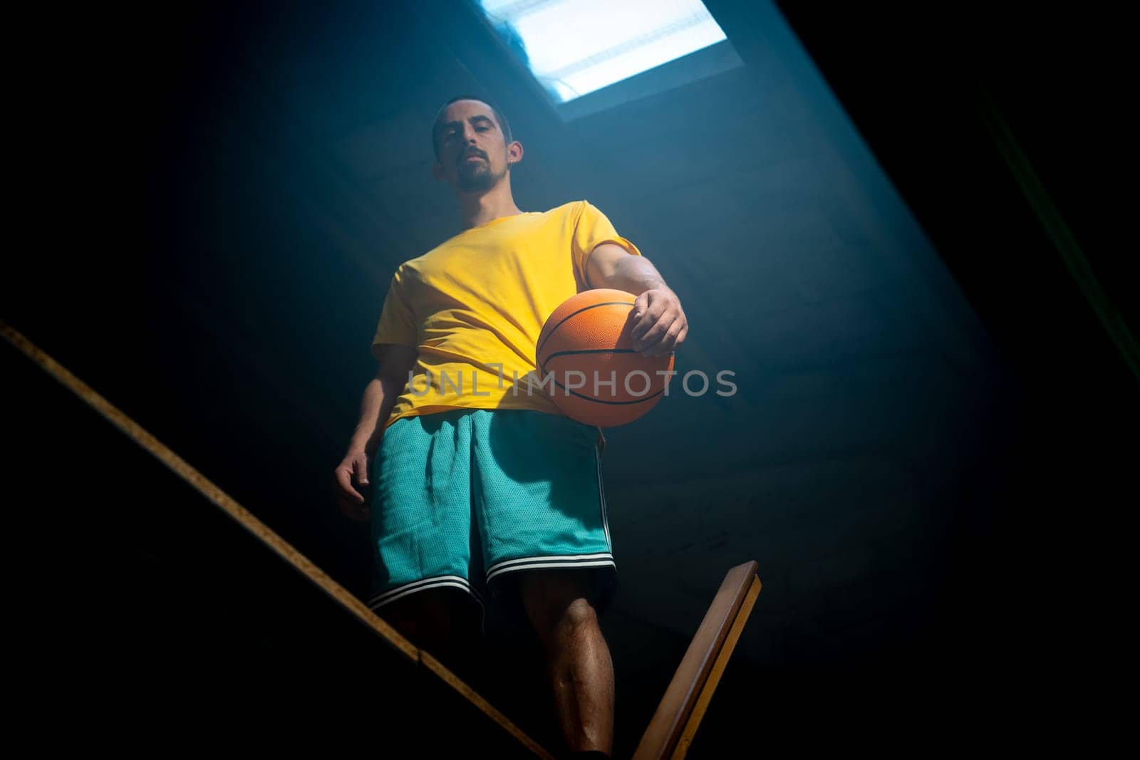 A determined basketball player, confidently poised with a ball in hand, is captured in a dynamic indoor setting