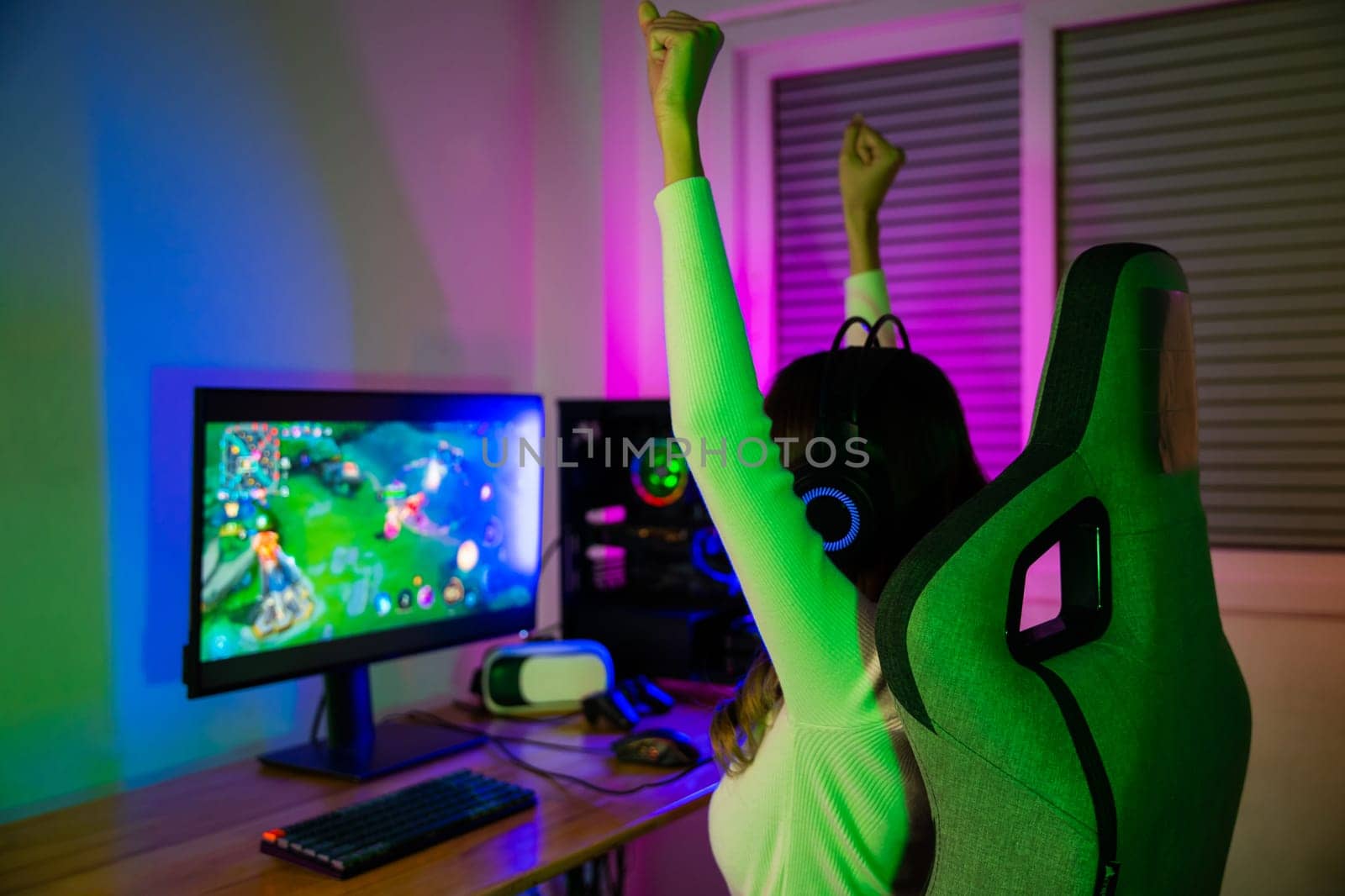 Winning. Young woman in gaming headphones playing video game online at home neon room feel excited, Happy Gamer young plays online video games computer she raises hands to wins tournament, E-Sport