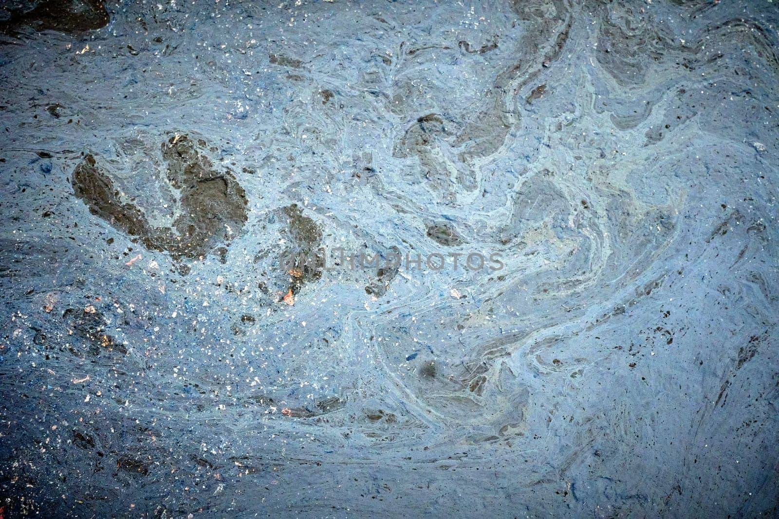 Foam and debris floating on polluted water create abstract shapes, highlighting environmental damage