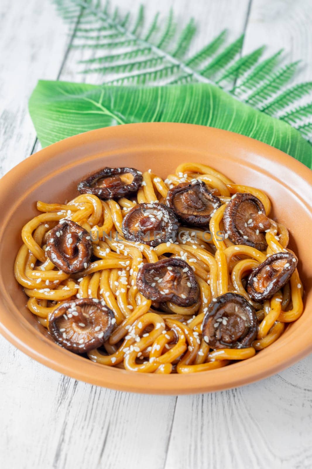 A portion of udon noodles with soy unagi mirin ginger sauce, shiitake and enoki mushrooms, and green onion