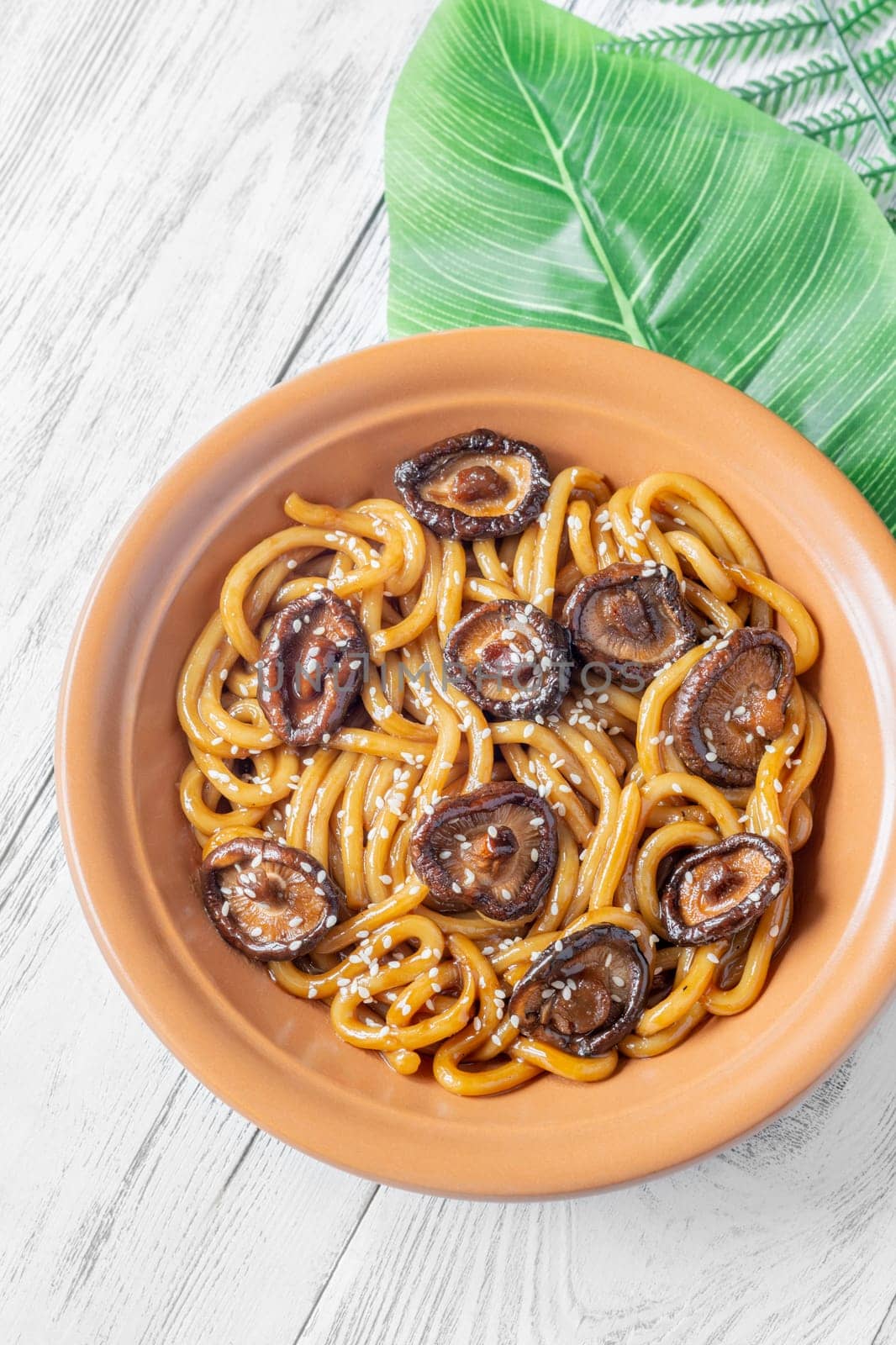 A portion of udon noodles with soy unagi mirin ginger sauce, shiitake and enoki mushrooms, and green onion
