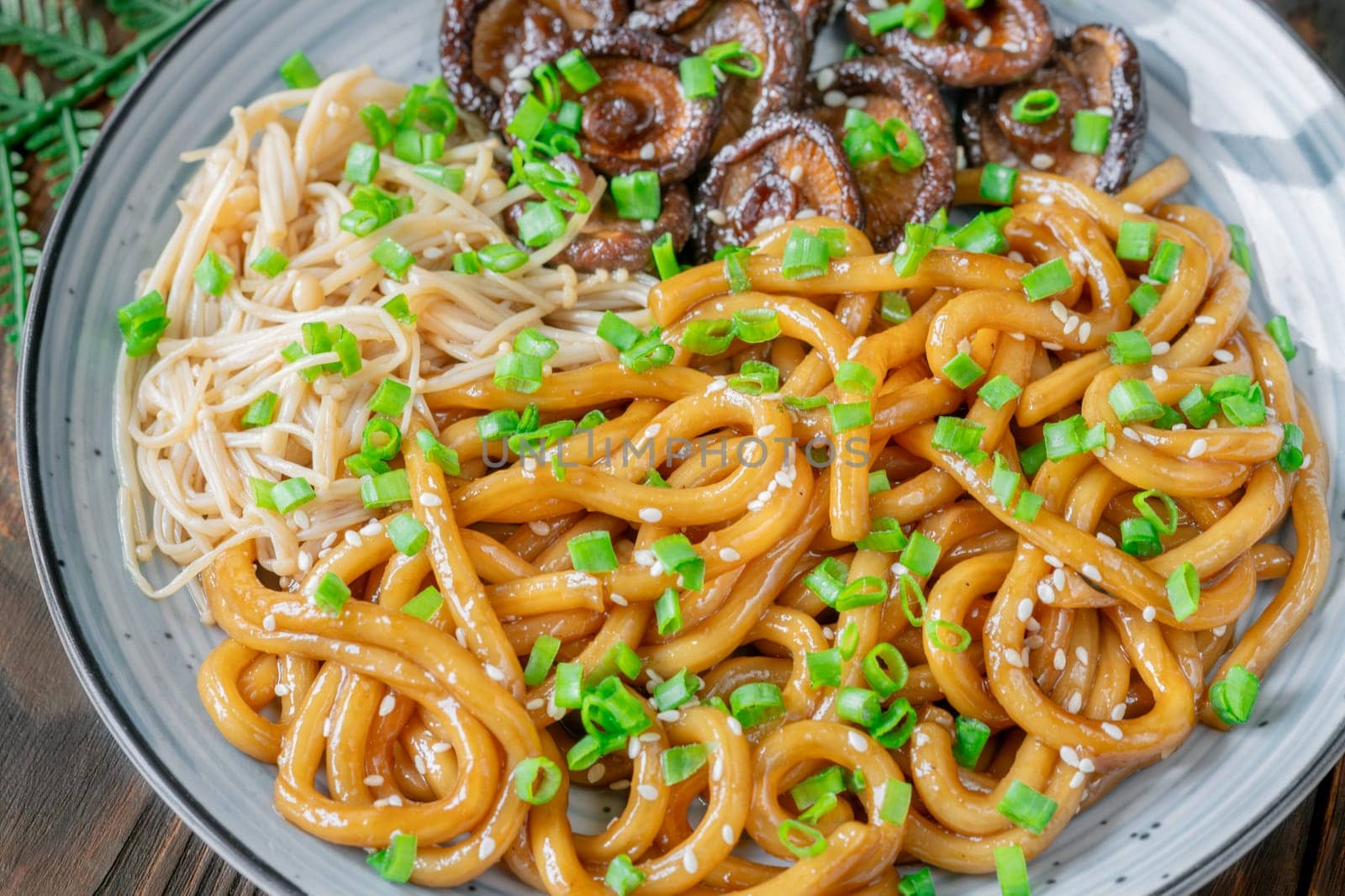 A portion of udon noodles with soy unagi mirin ginger sauce, shiitake and enoki mushrooms, and green onion