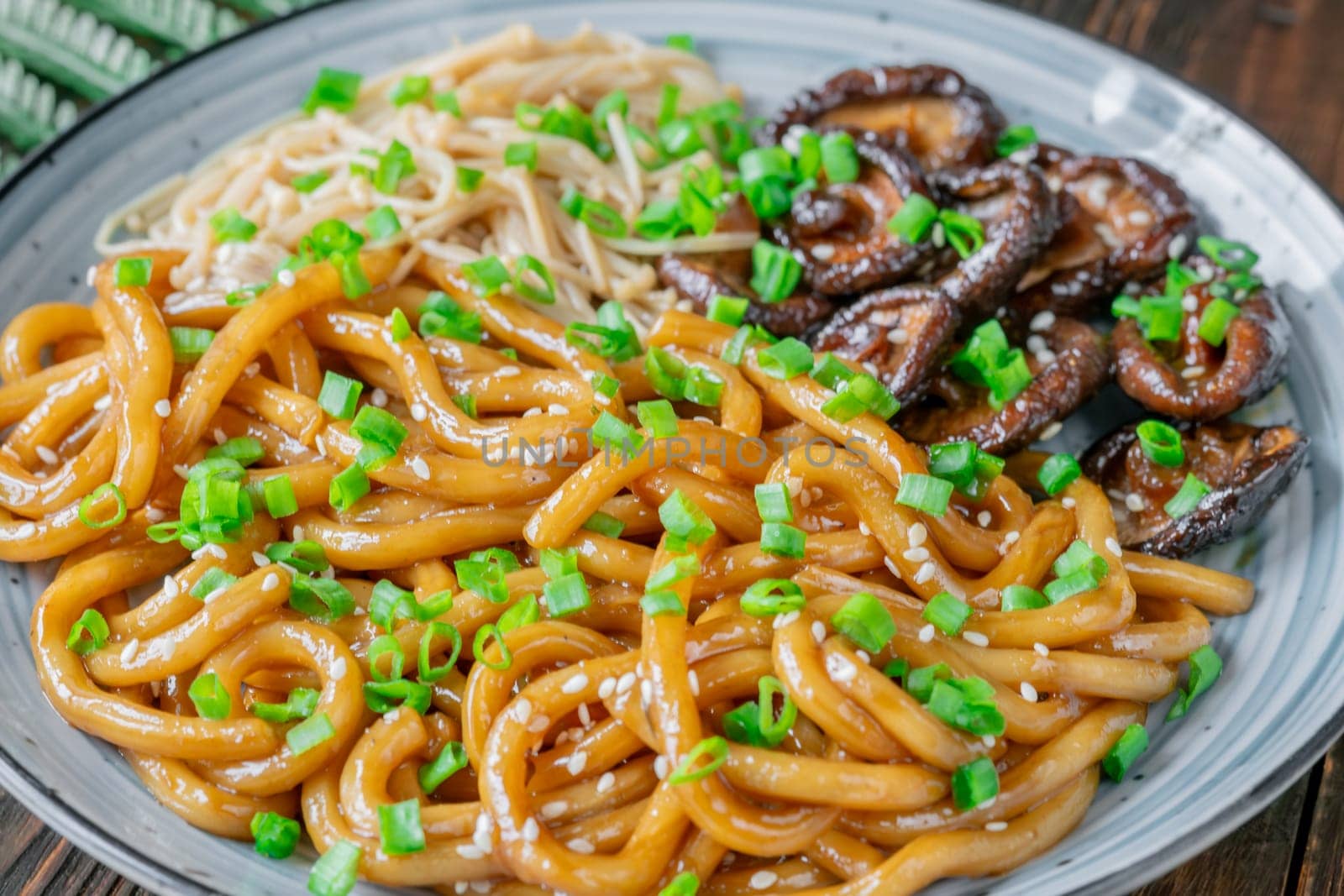 A portion of udon noodles with soy unagi mirin ginger sauce, shiitake and enoki mushrooms, and green onion