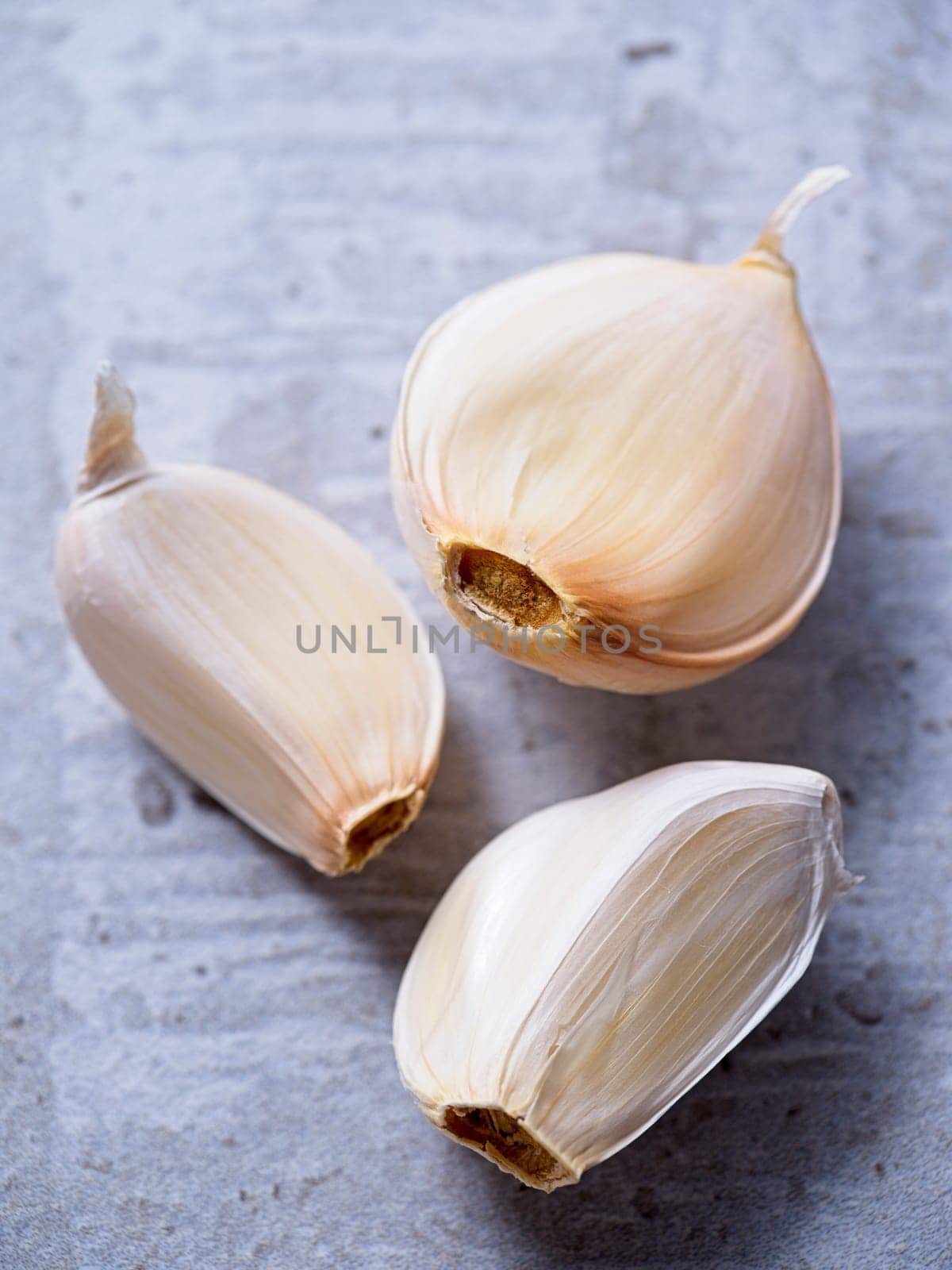 A flat lay photo of three garlic cloves on a table.