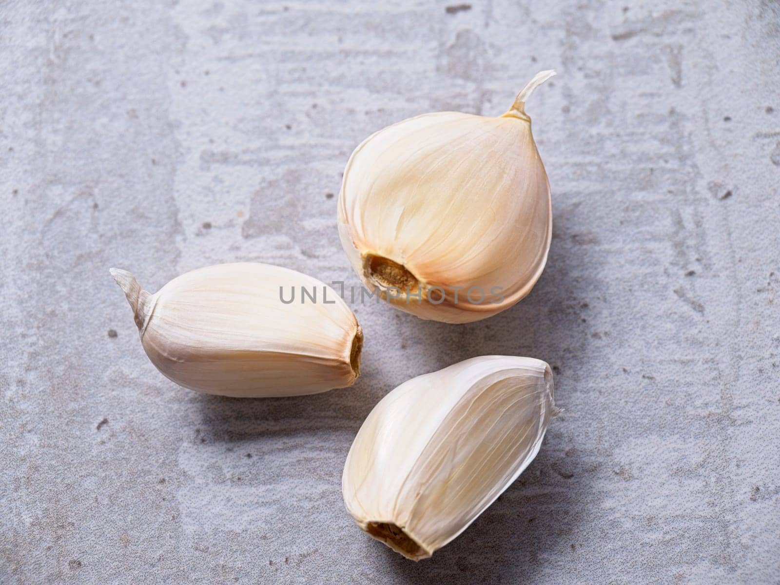 A flat lay photo of three garlic cloves on a table.