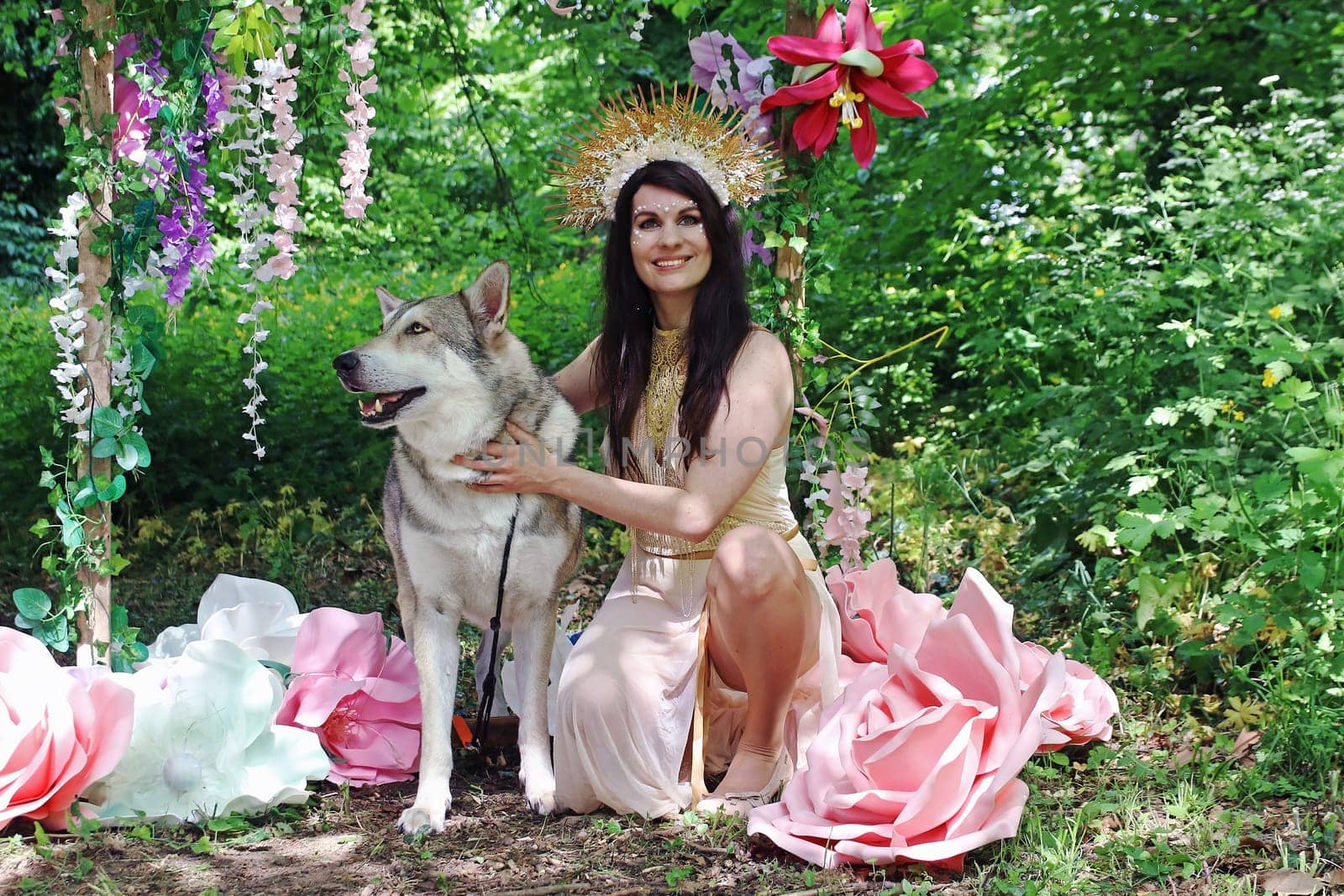 Fantasy-Foto von einer als Fee verkleideten Frau mit einem Wolfshund im Märchenwald