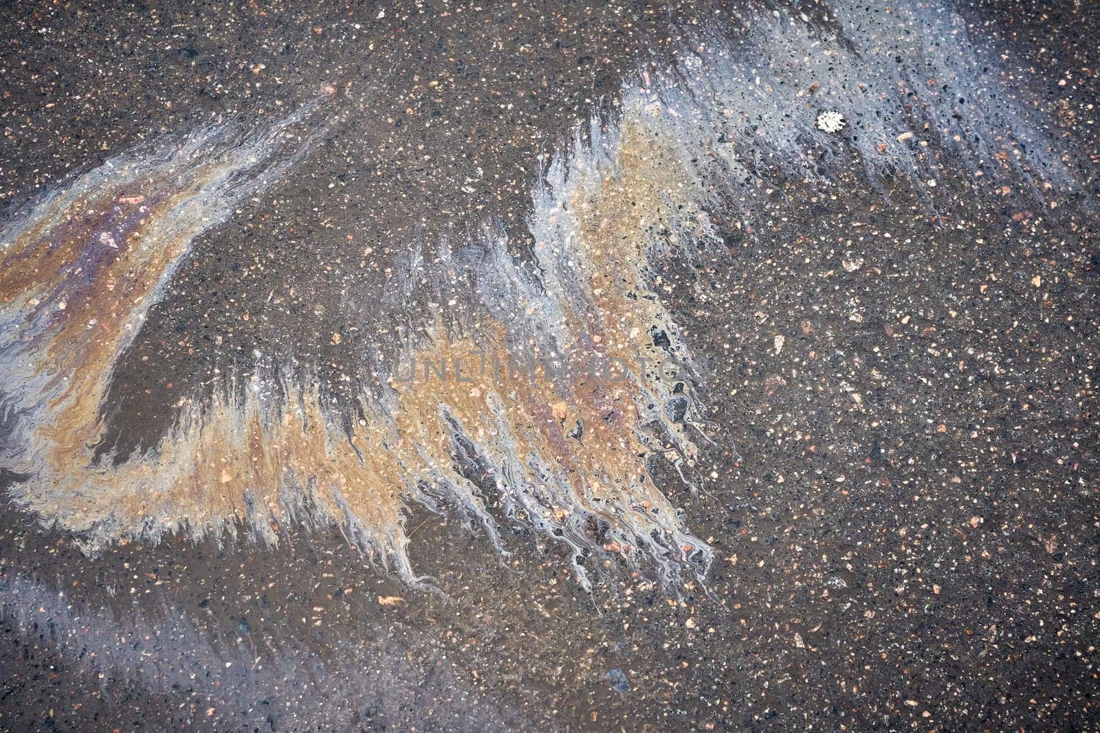 Gasoline or oil is creating colorful patterns on asphalt road.