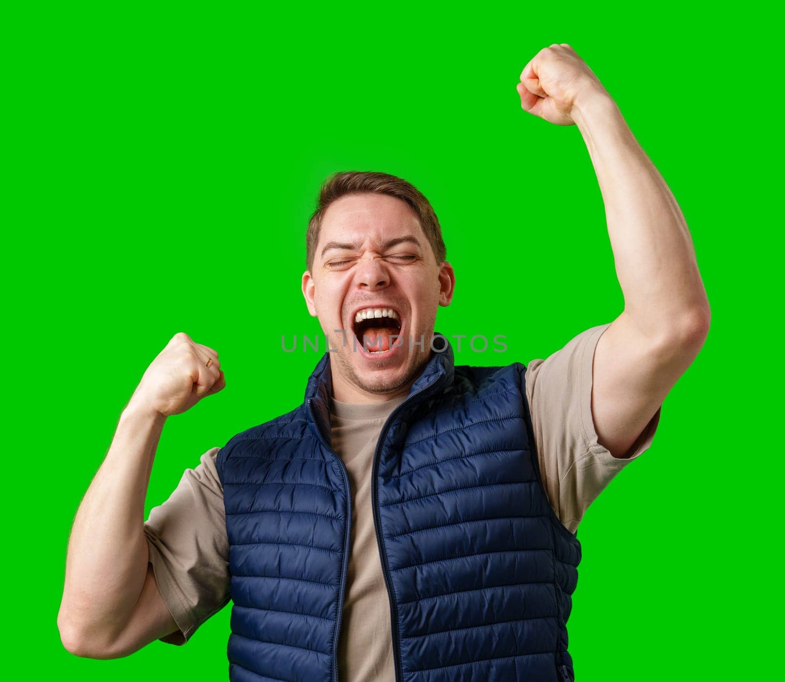 Man celebrating with raised fists in front of a bright green background in studio