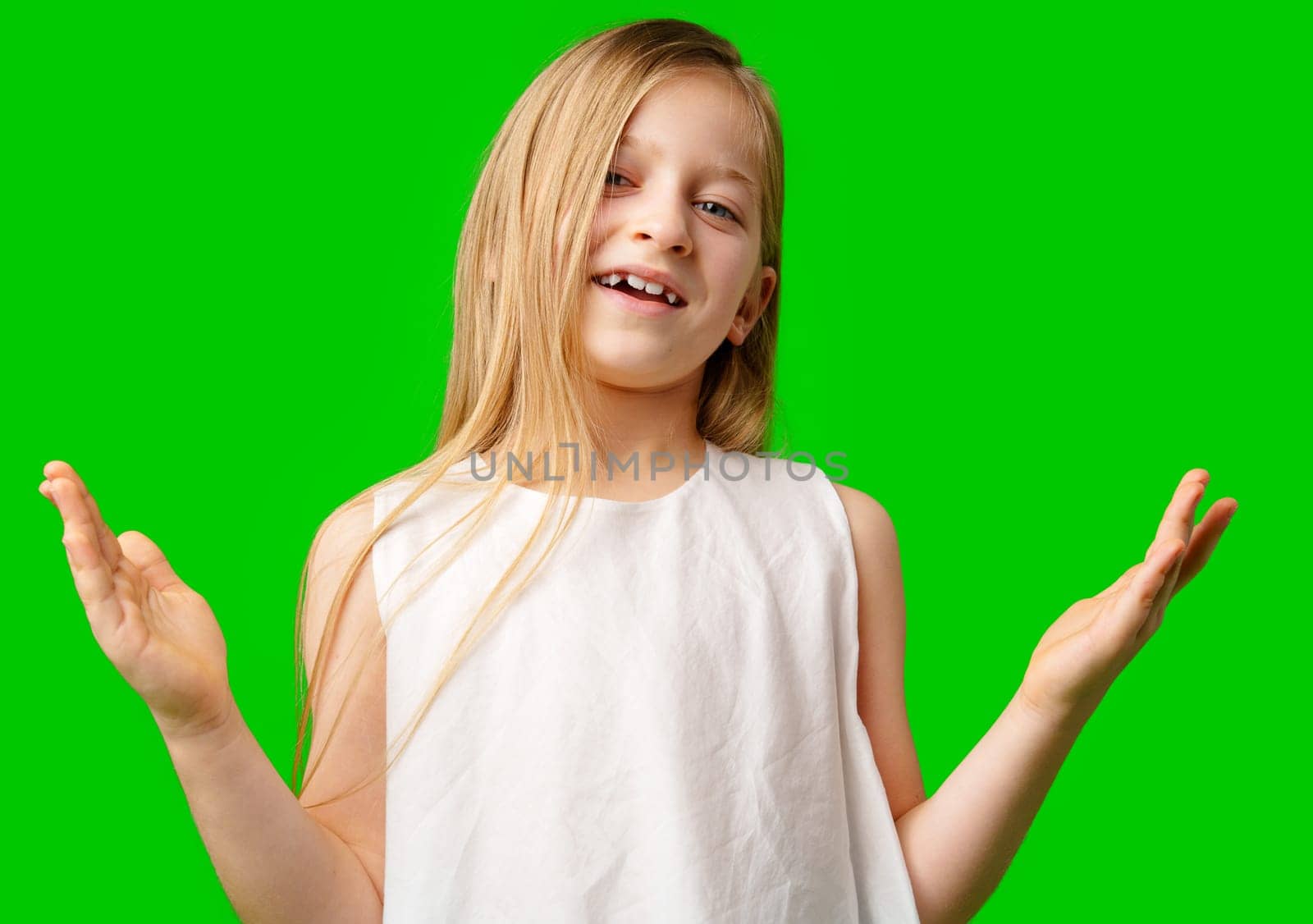 A young girl with long hair in a white dress poses with open arms against a vibrant green background