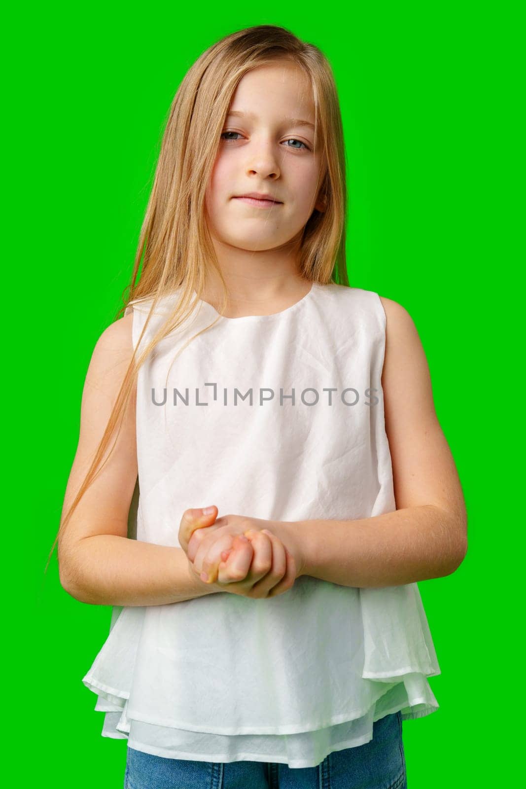 Young girl standing confidently against a bright green background in studio
