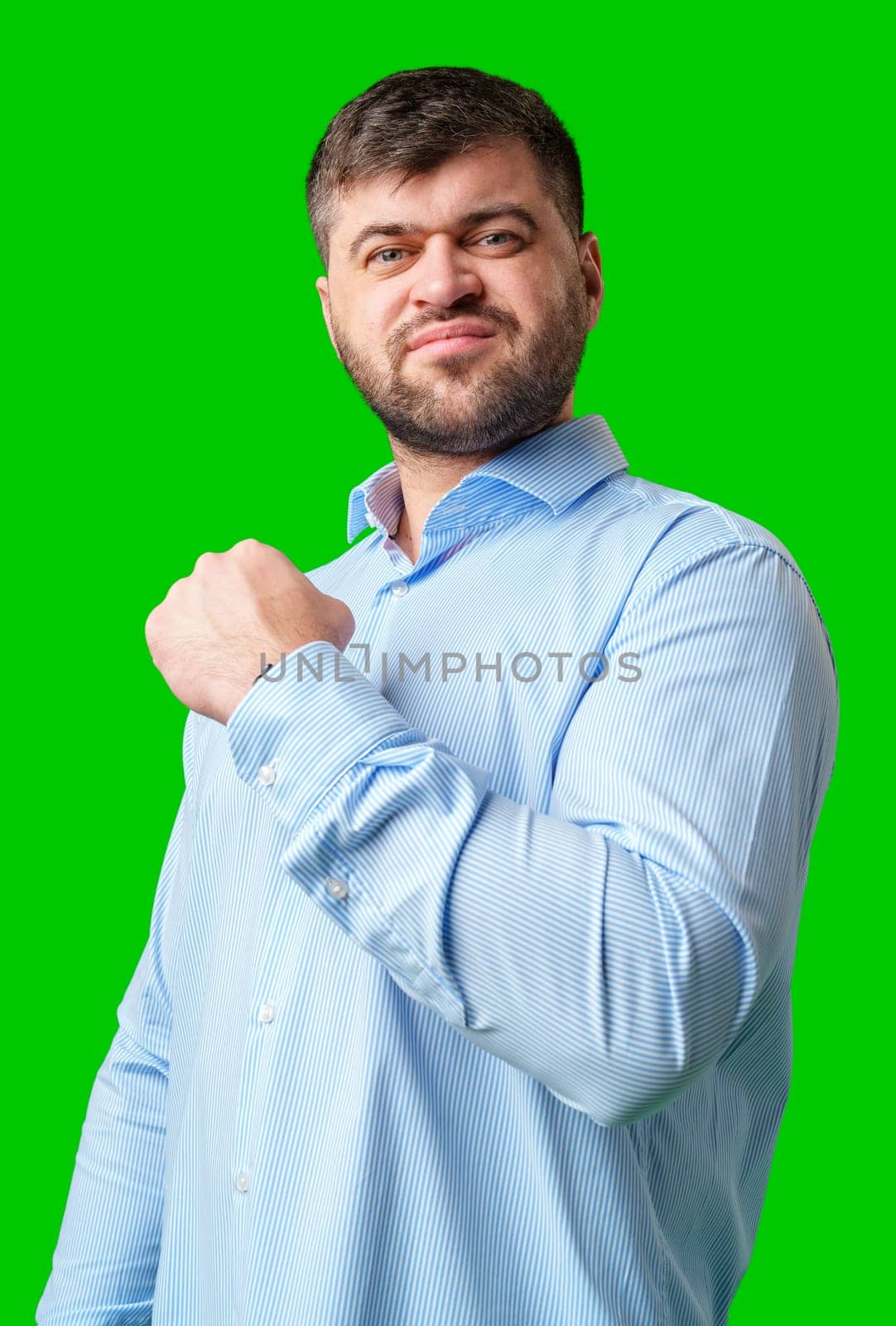A strong man with fists raised, smiling confidently, on a bright green background in studio